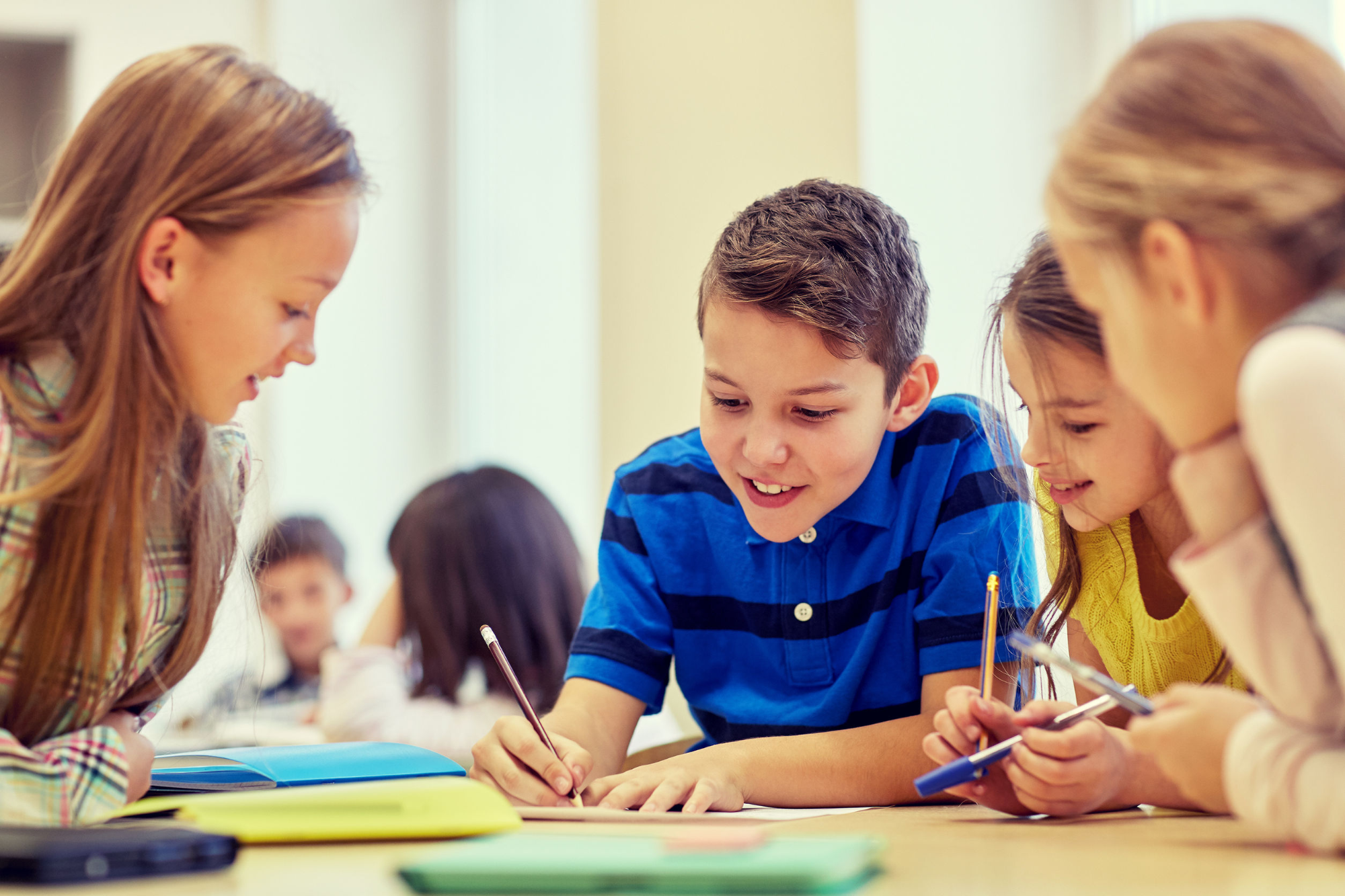 a group of children sitting at a table writing on paper