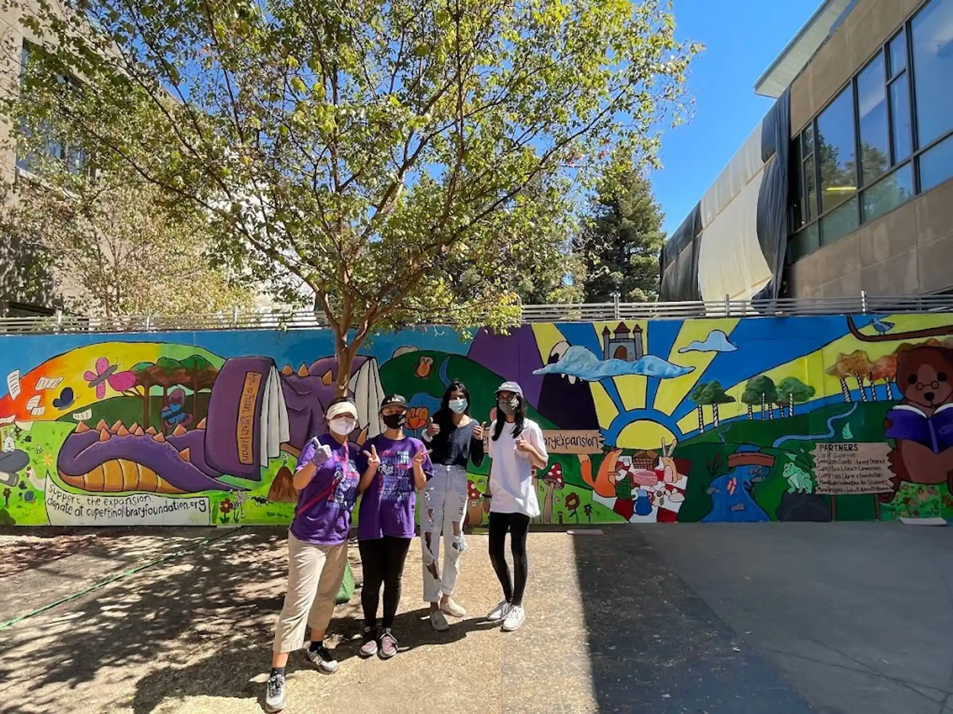 a group of people posing for a photo in front of a wall with art