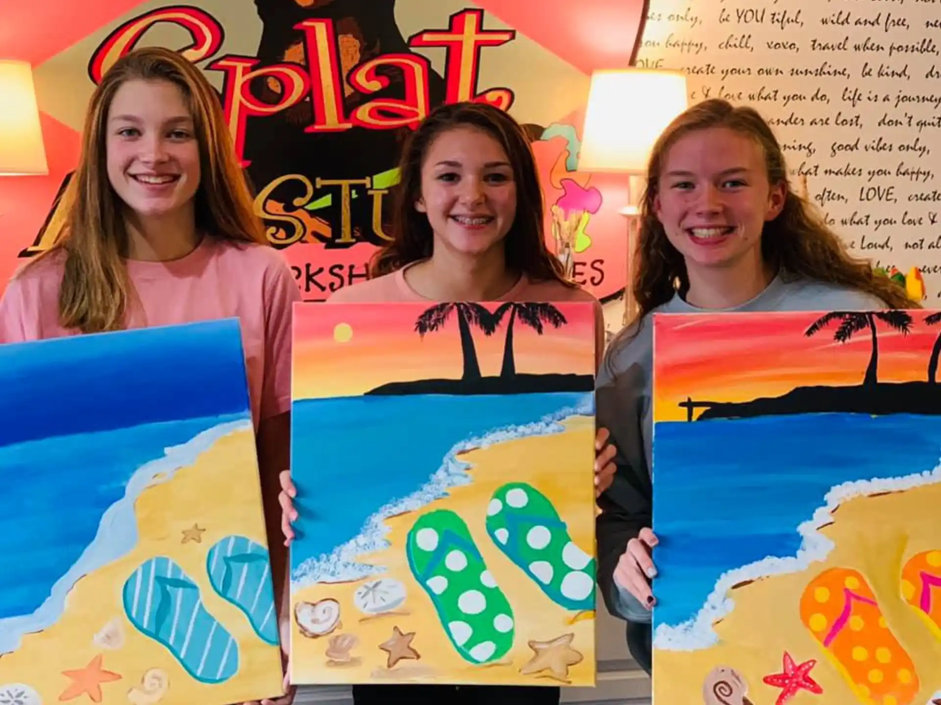a group of girls holding up artwork