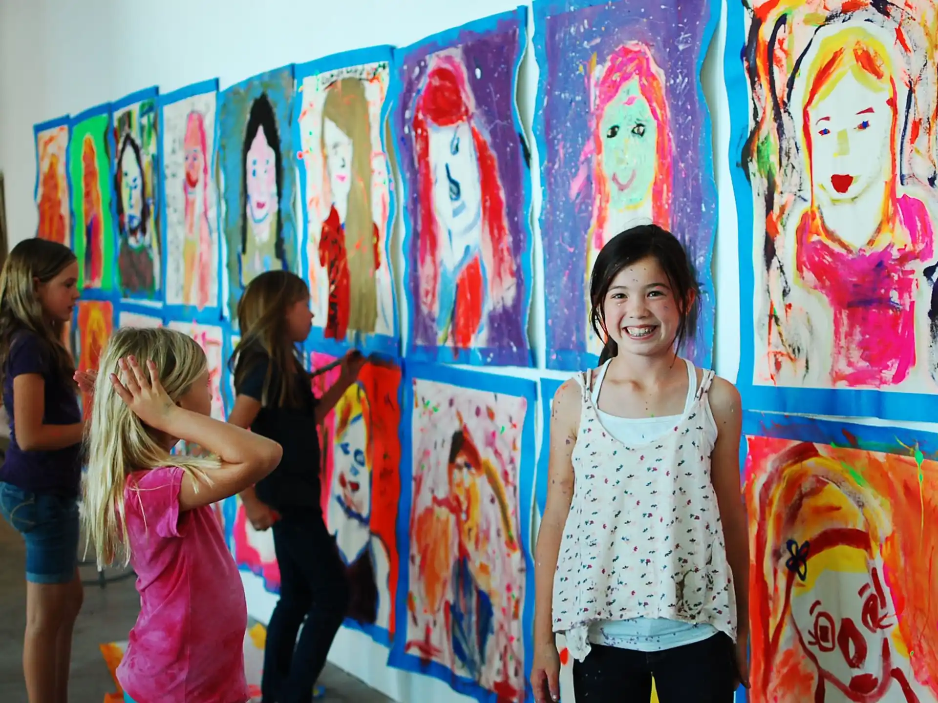 a group of children standing in front of a wall with art