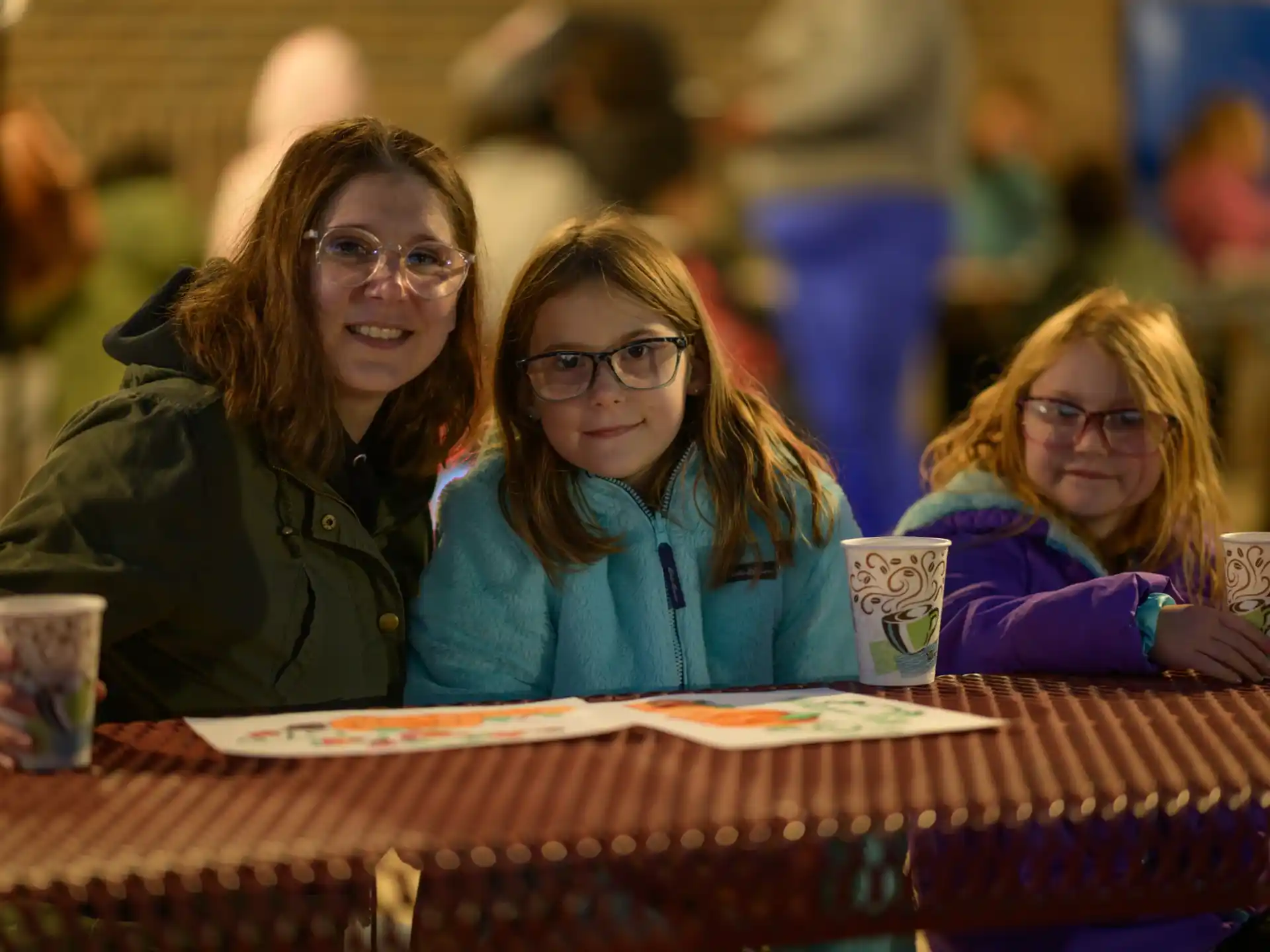 a group of women sitting at a table with cups and a menu