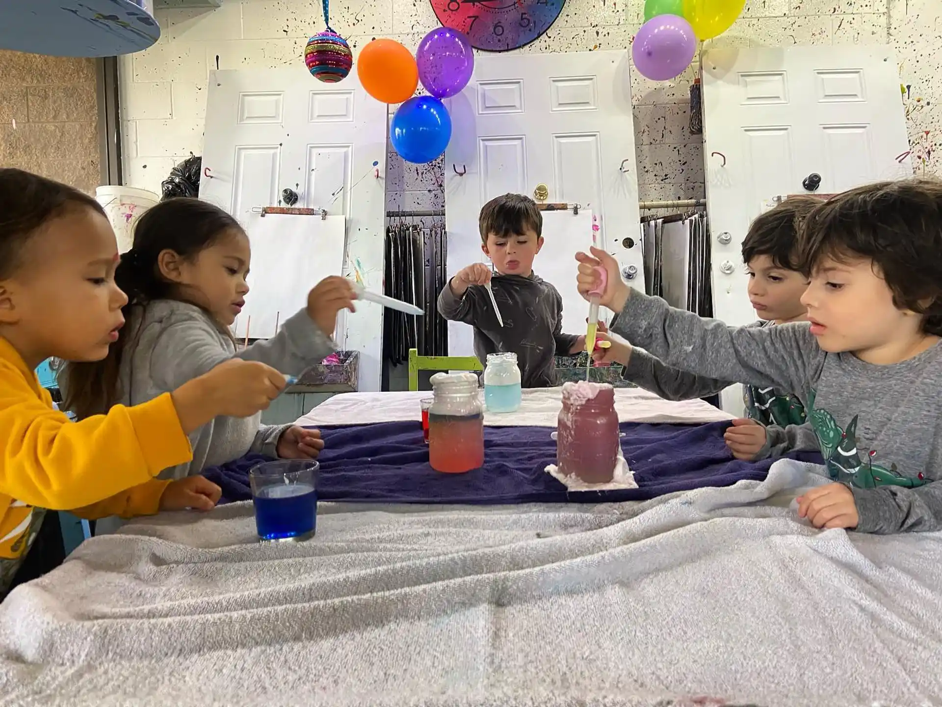 a group of children sitting at a table with food and drinks