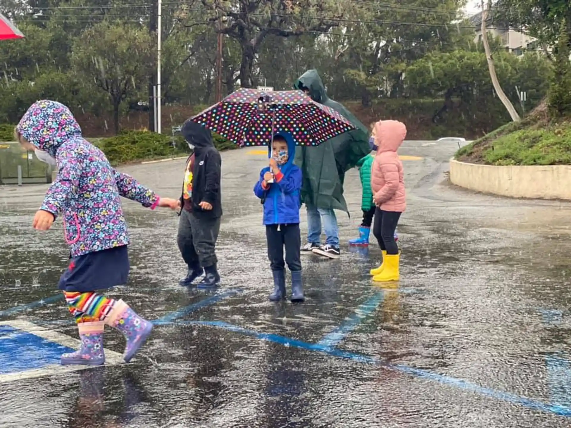 a group of people stand in the rain with an umbrella