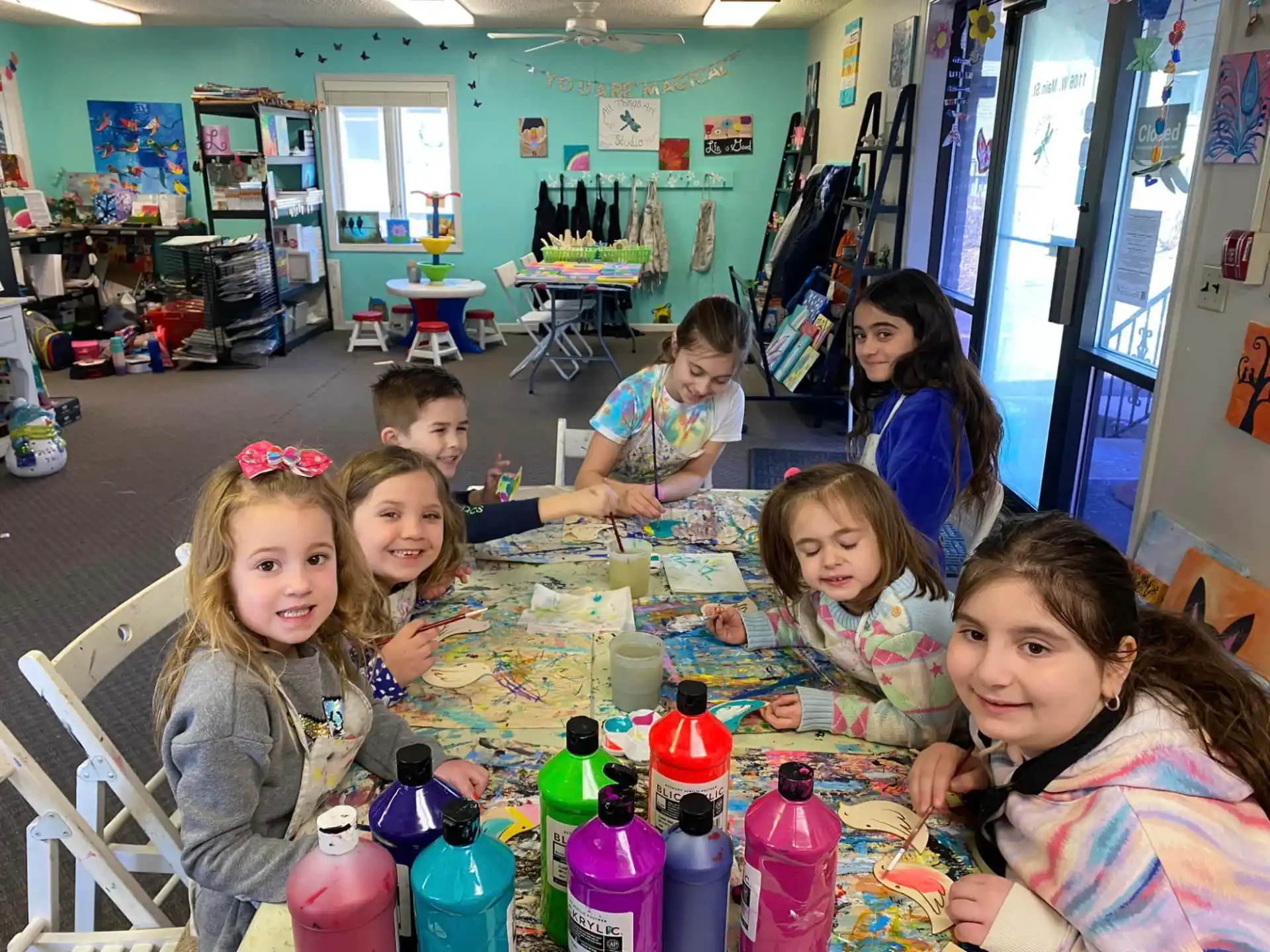 a group of children sitting at a table with bottles and cans