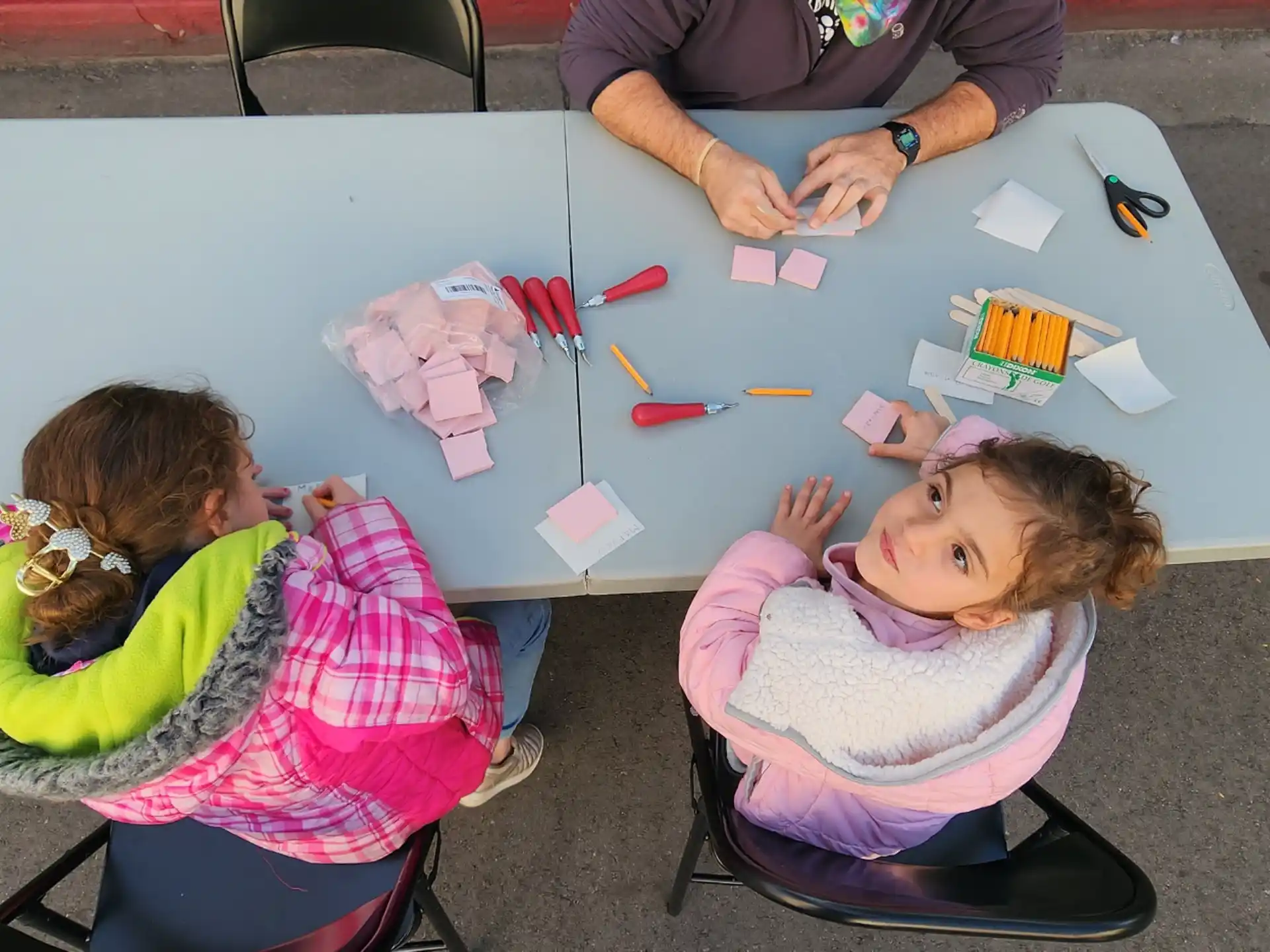 a group of children sitting at a table with colorful paper on it