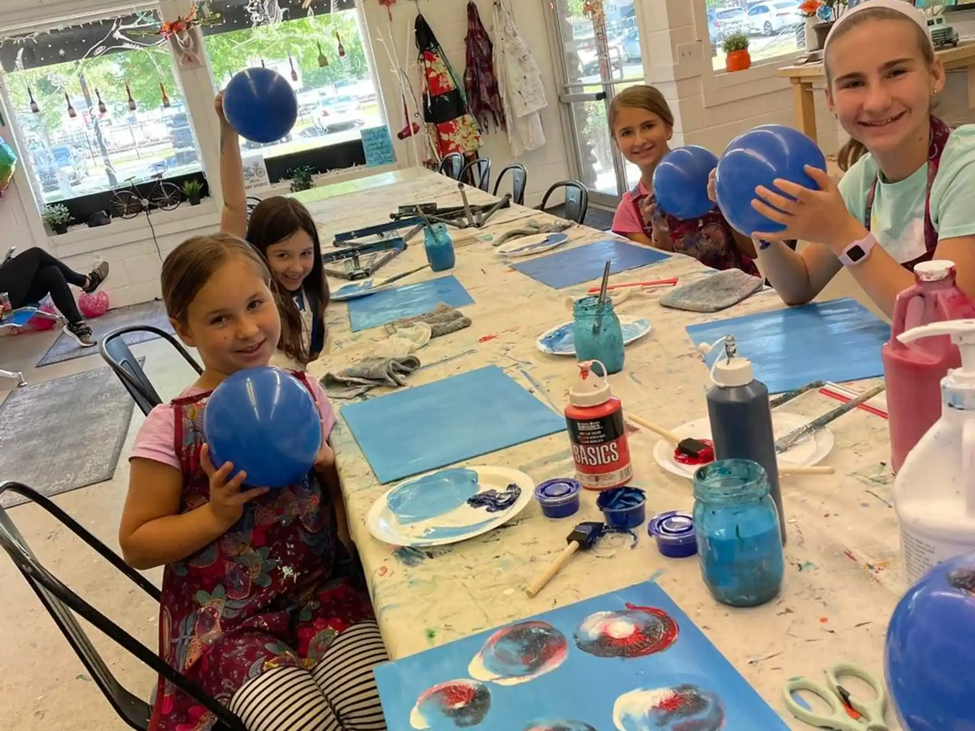 a group of children sitting around a table with blue plates and cups