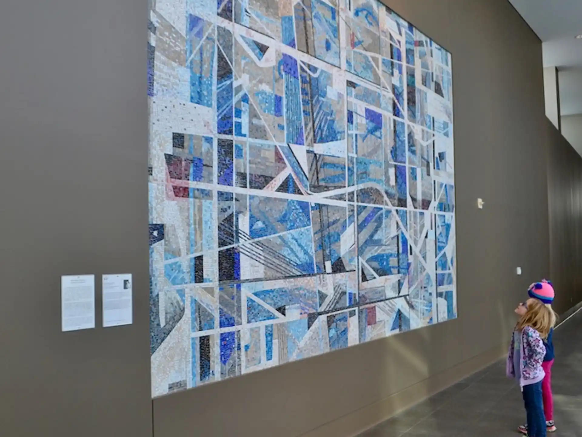 a girl standing next to a wall with a painting on it