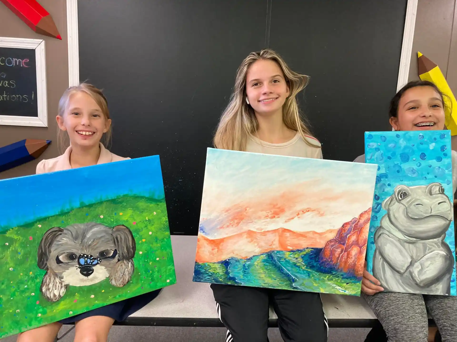 a group of girls holding paintings