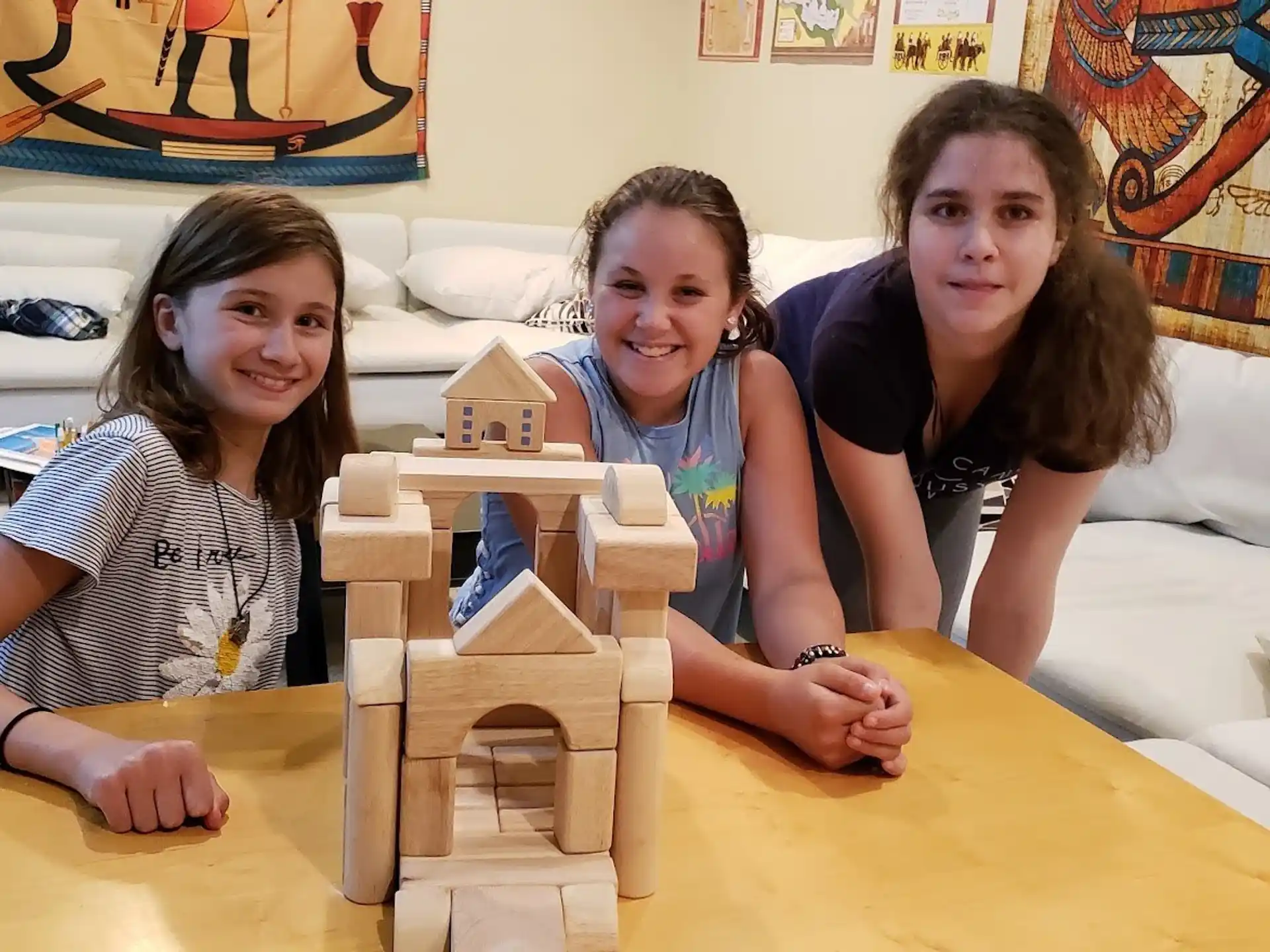 a group of girls sitting on a bed with a cardboard box