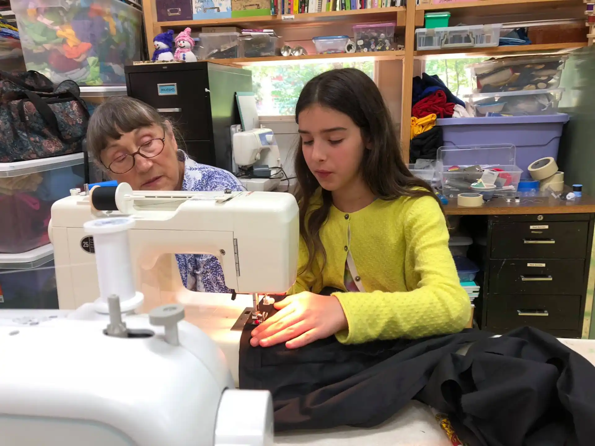 a person and a girl in a room with a sewing machine