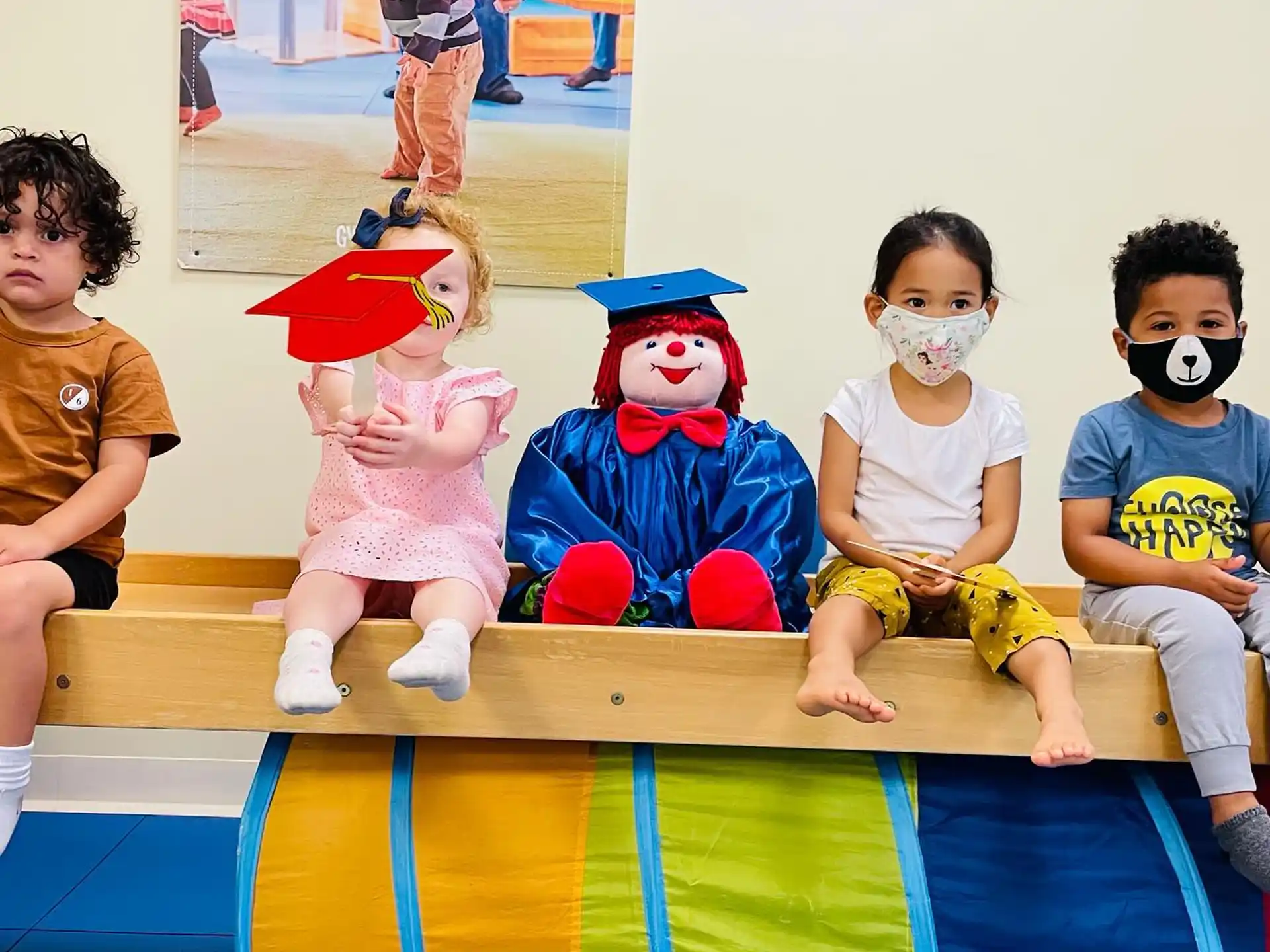 a group of children sitting on a bench with clowns