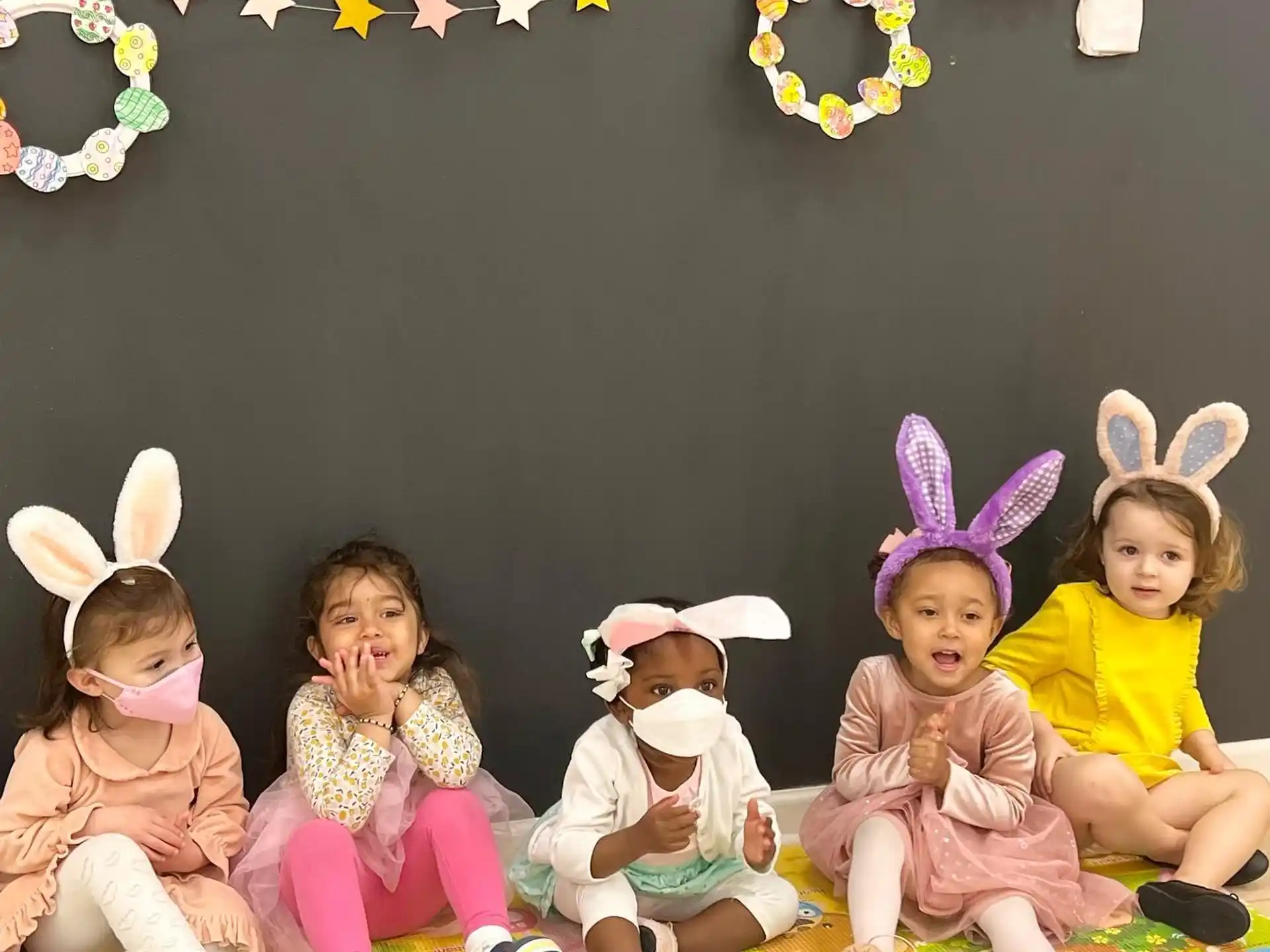 a group of children sitting on the floor with rabbit ears and a star