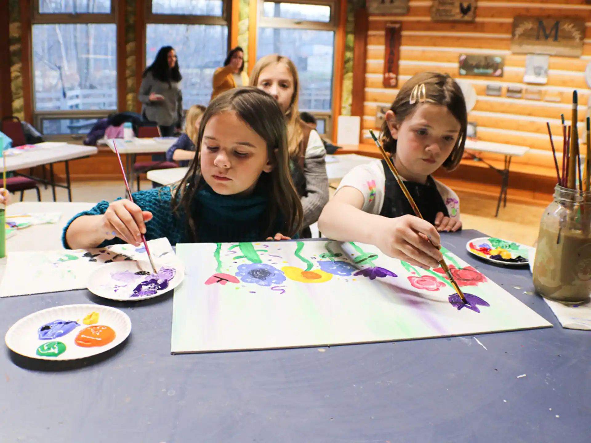 a group of girls sitting at a table painting