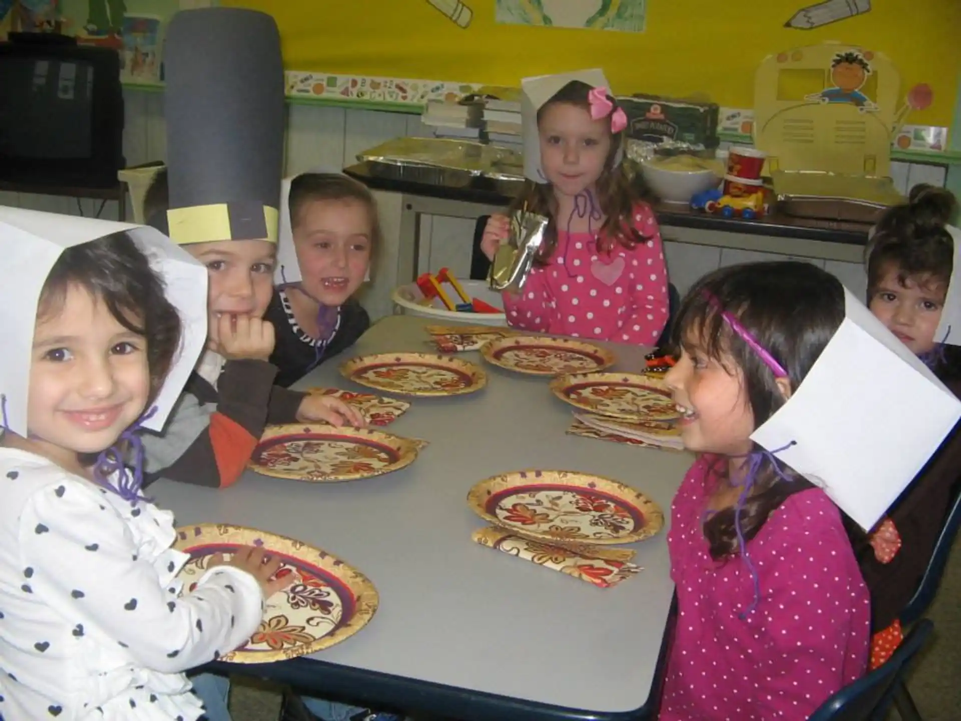 a group of children sitting at a table with food on it