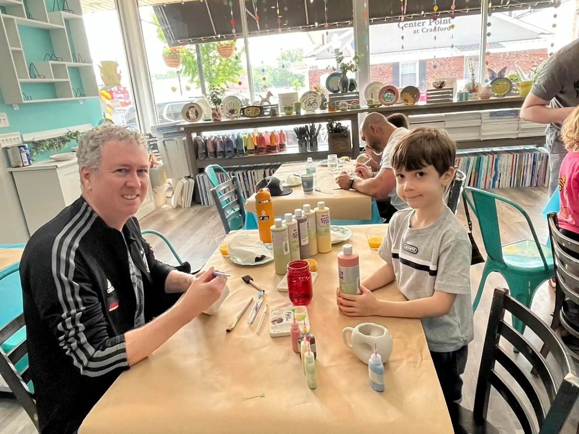 a person and a boy sitting at a table with food and drinks