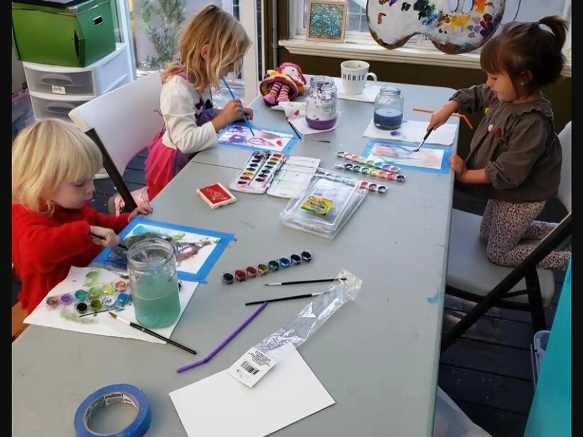 a group of children sitting at a table with tools and papers