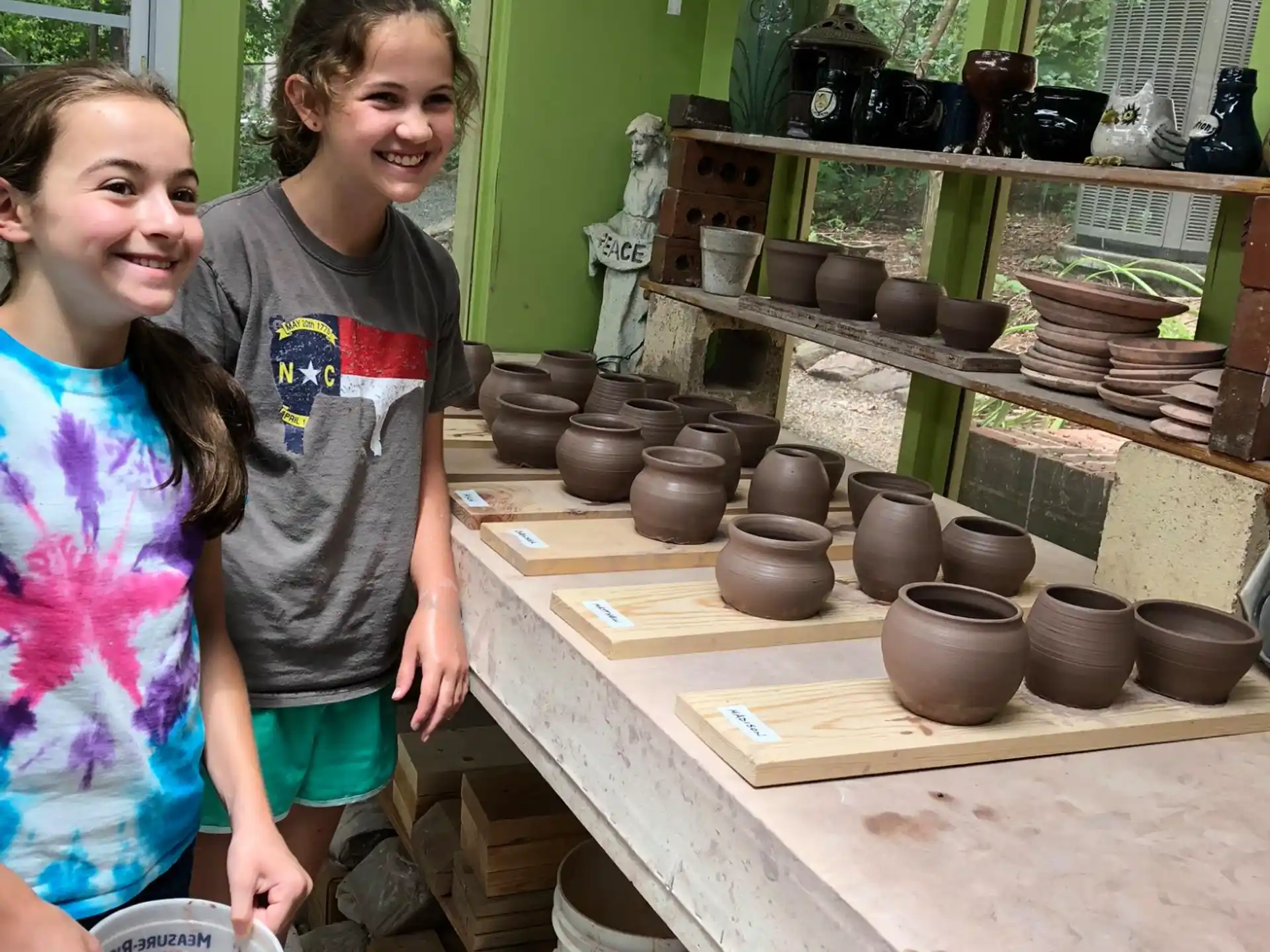 a couple of children standing next to a table with pots and pans