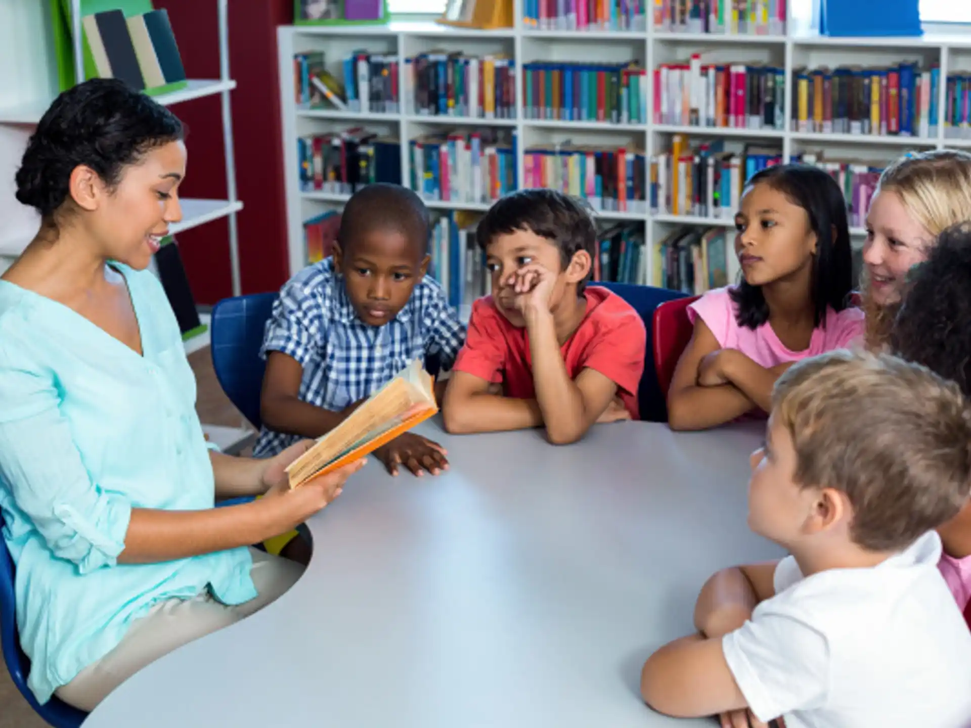 a group of children sitting at a table in a library