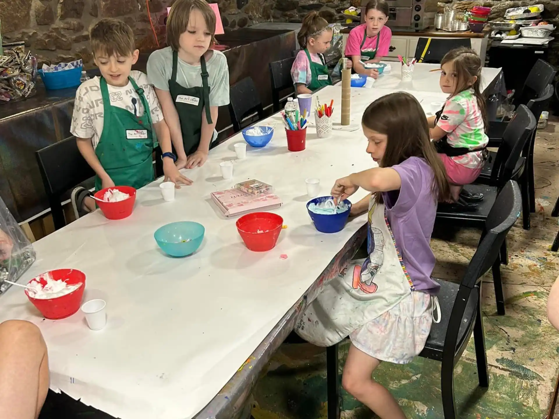 a group of children sitting around a table with food