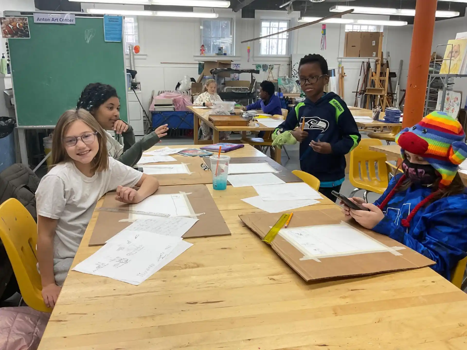 a group of people sitting at a table with papers and a person standing behind them
