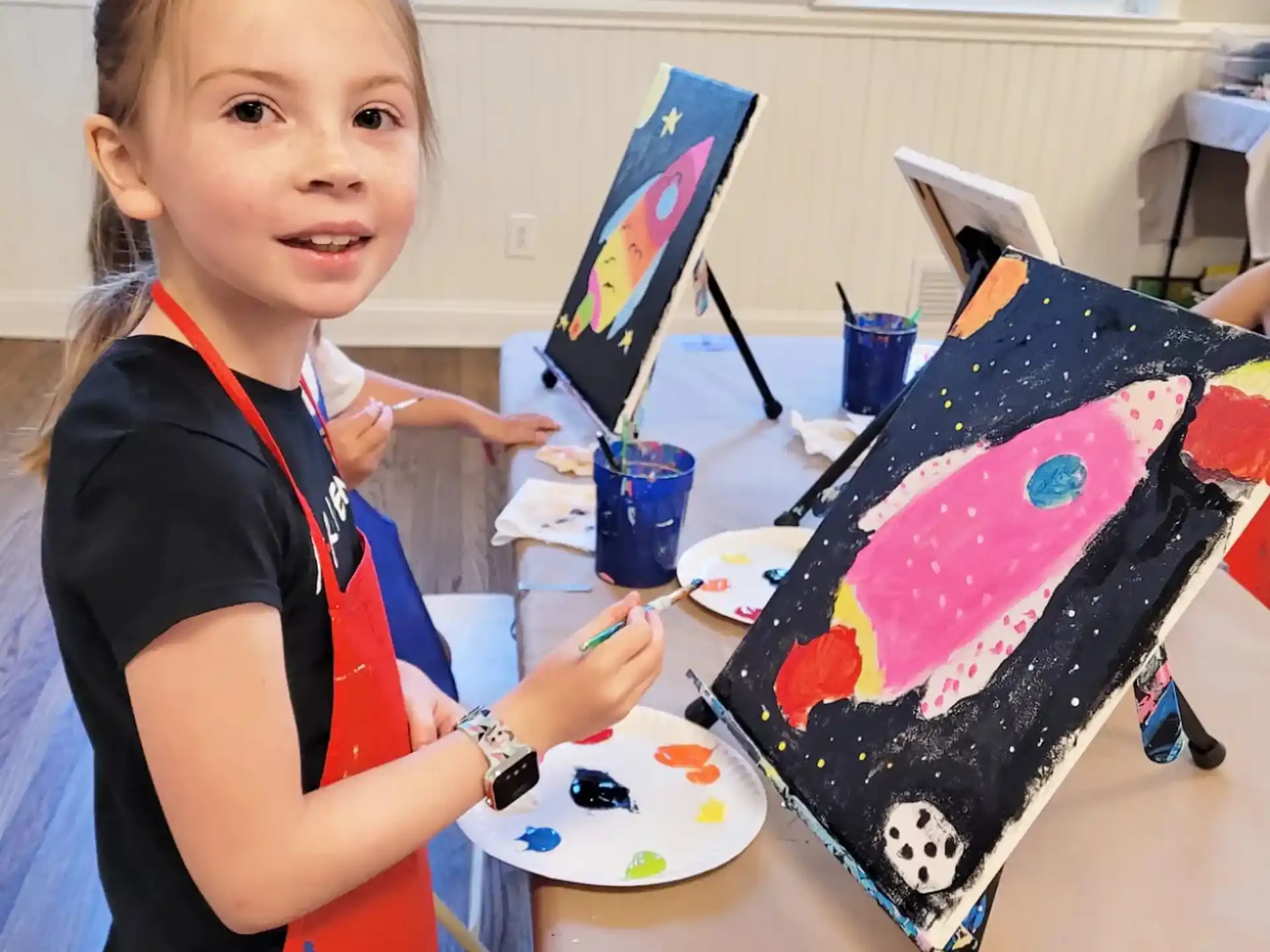a girl holding a plate with a painting on it