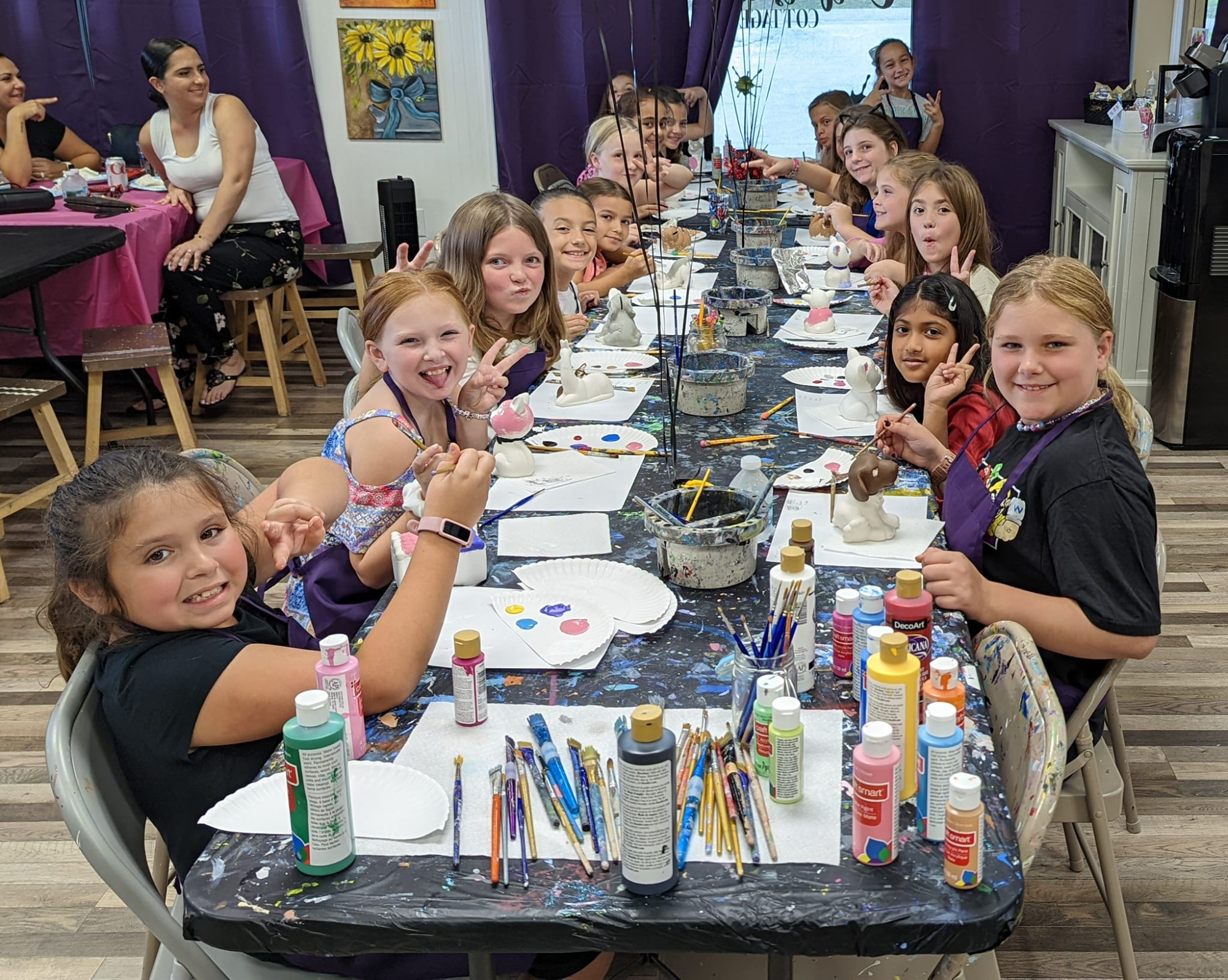 a group of children sitting at a table with food and drinks
