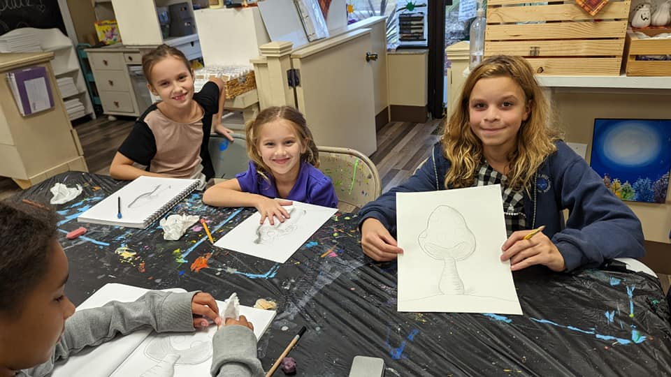 a group of children sitting at a table with papers and pencils