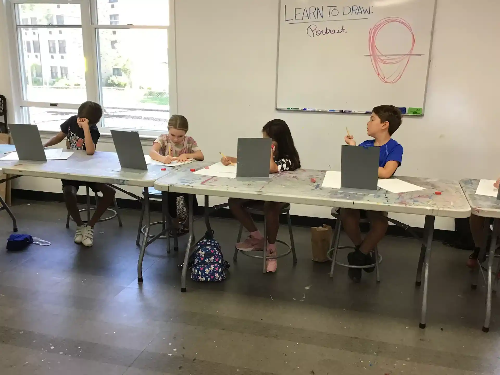 a group of children sitting at a table with laptops