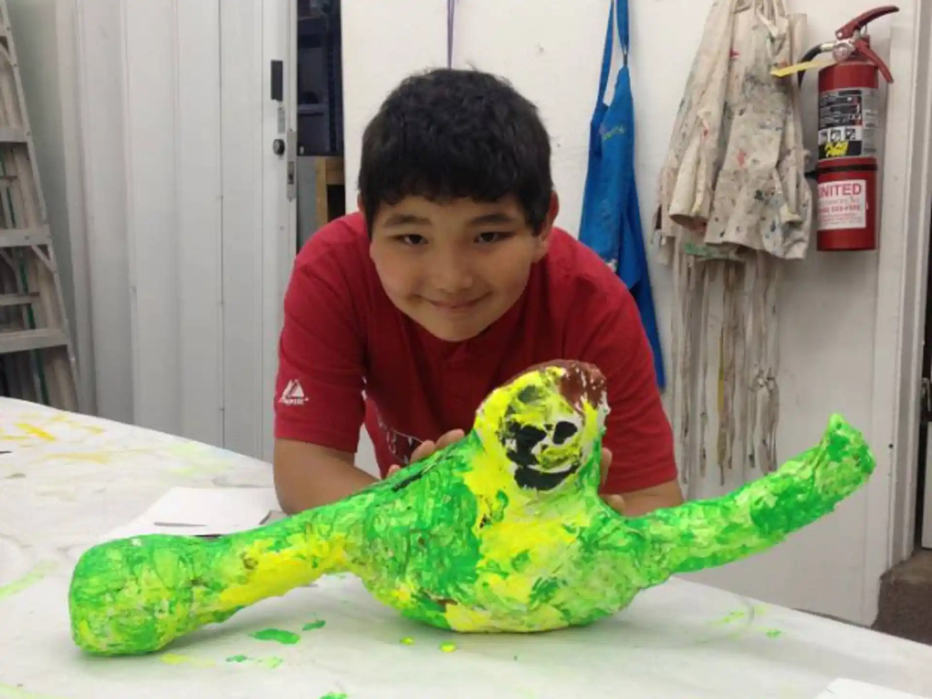 a boy sitting at a table with a green lizard on it