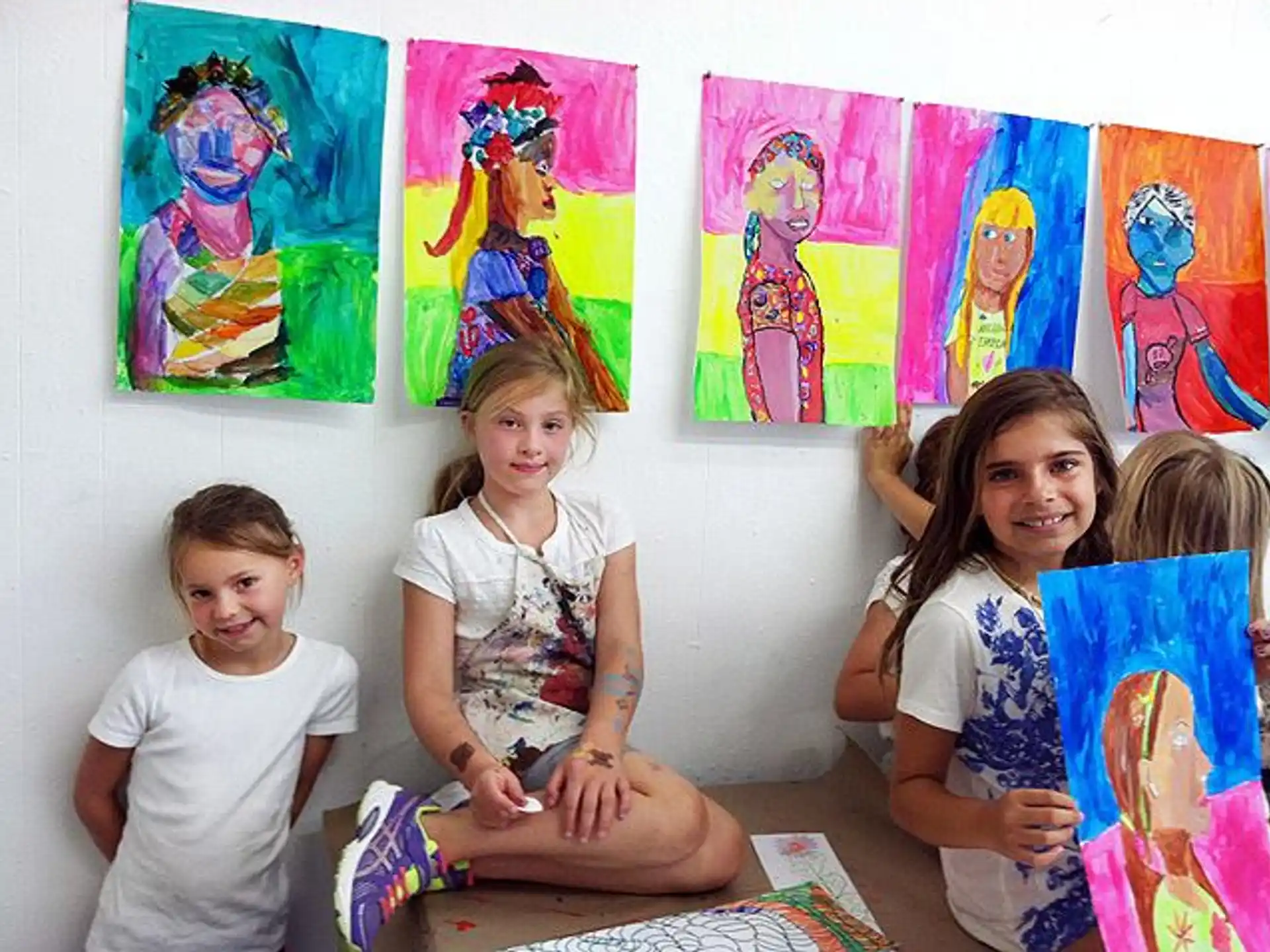 a group of children posing for a photo in front of a wall of art