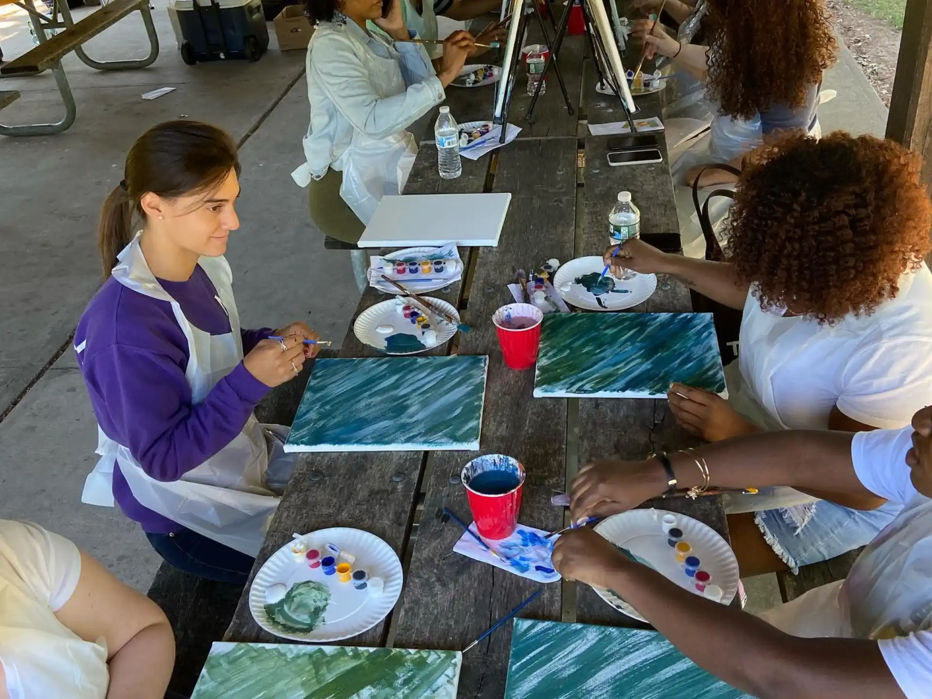 a group of people sitting at a table painting