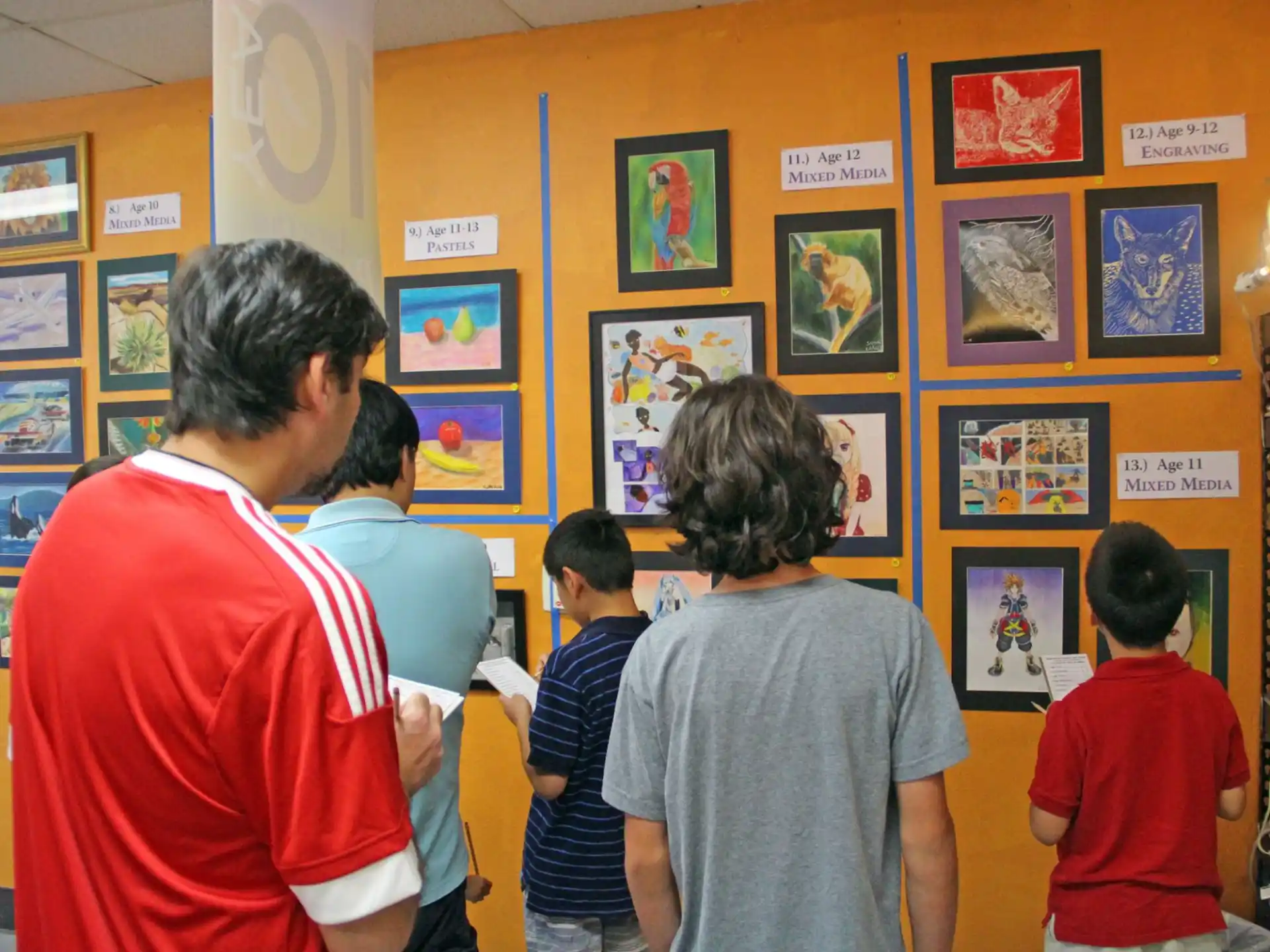 a group of people looking at pictures on a wall