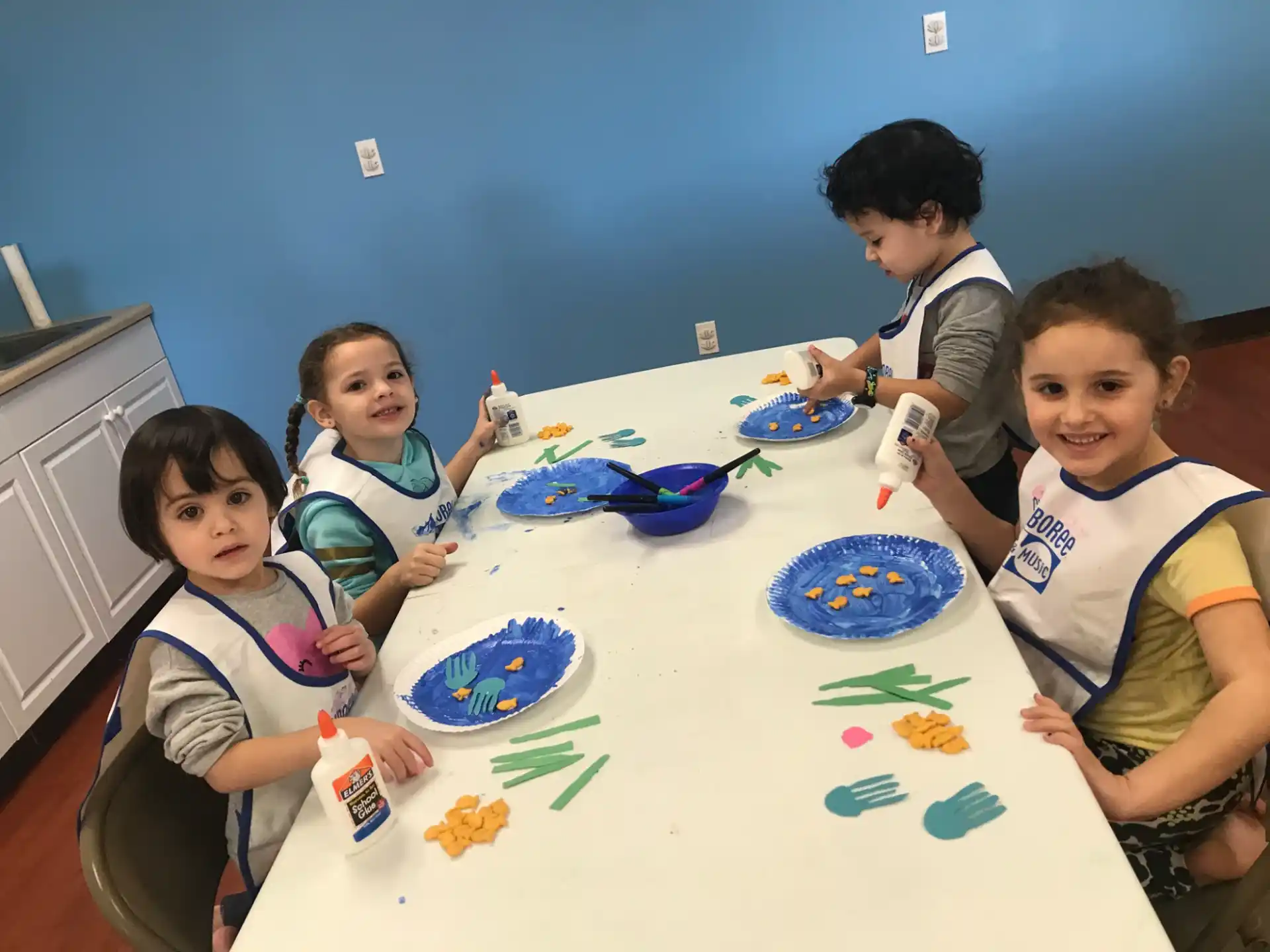 a group of children sitting at a table with food and drinks