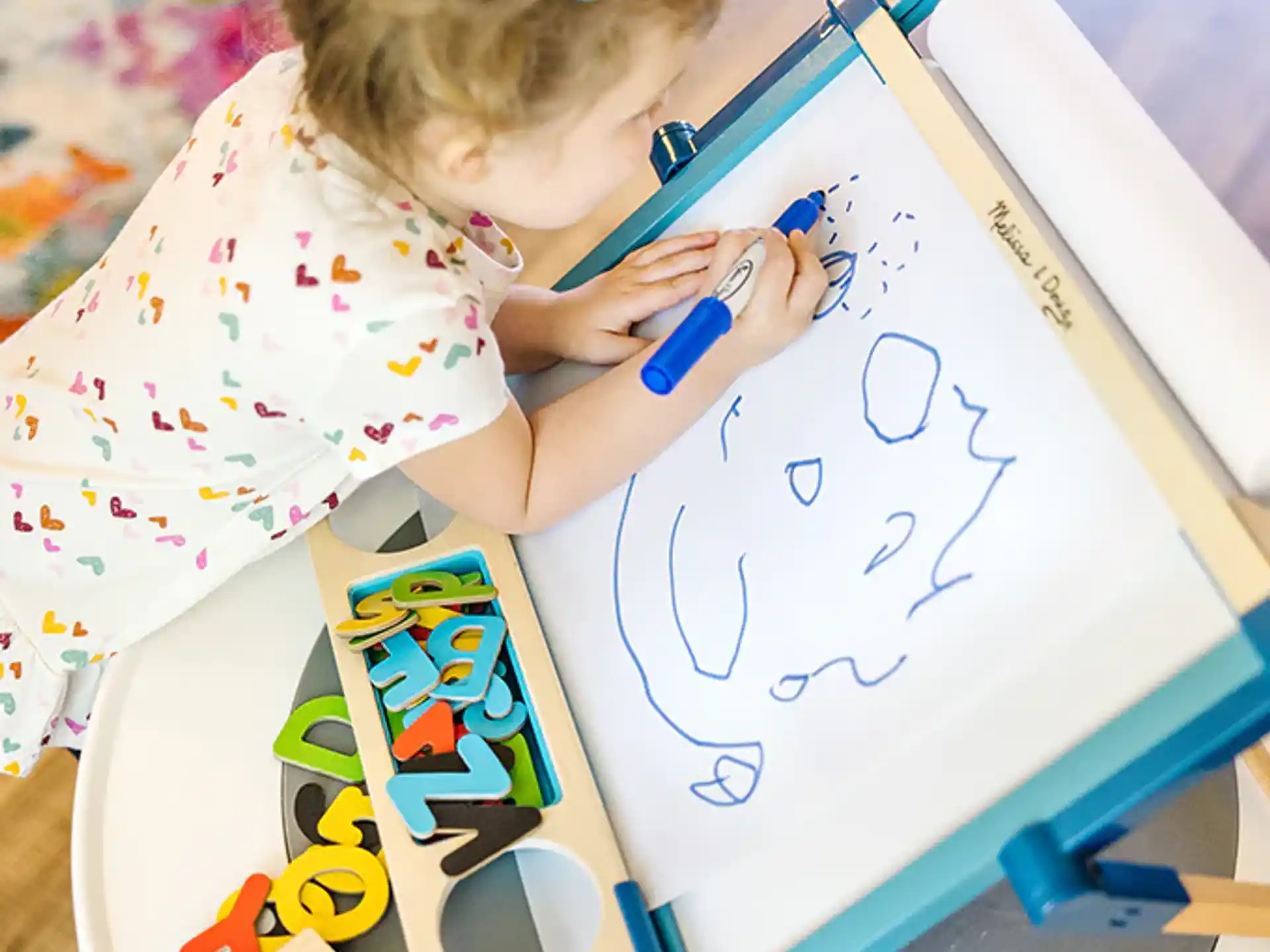 a young girl drawing on a white board