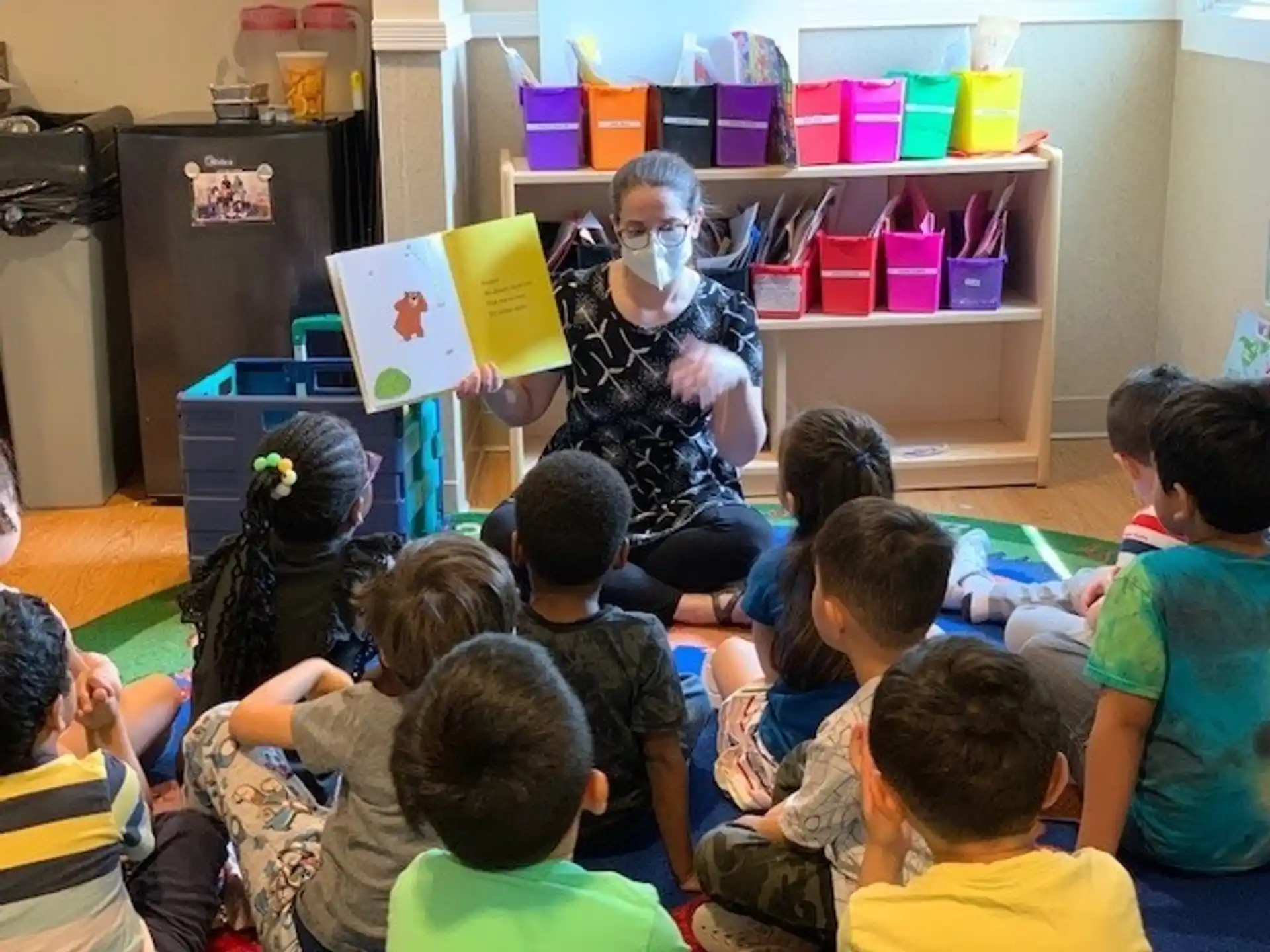 a person reading a book to a group of children