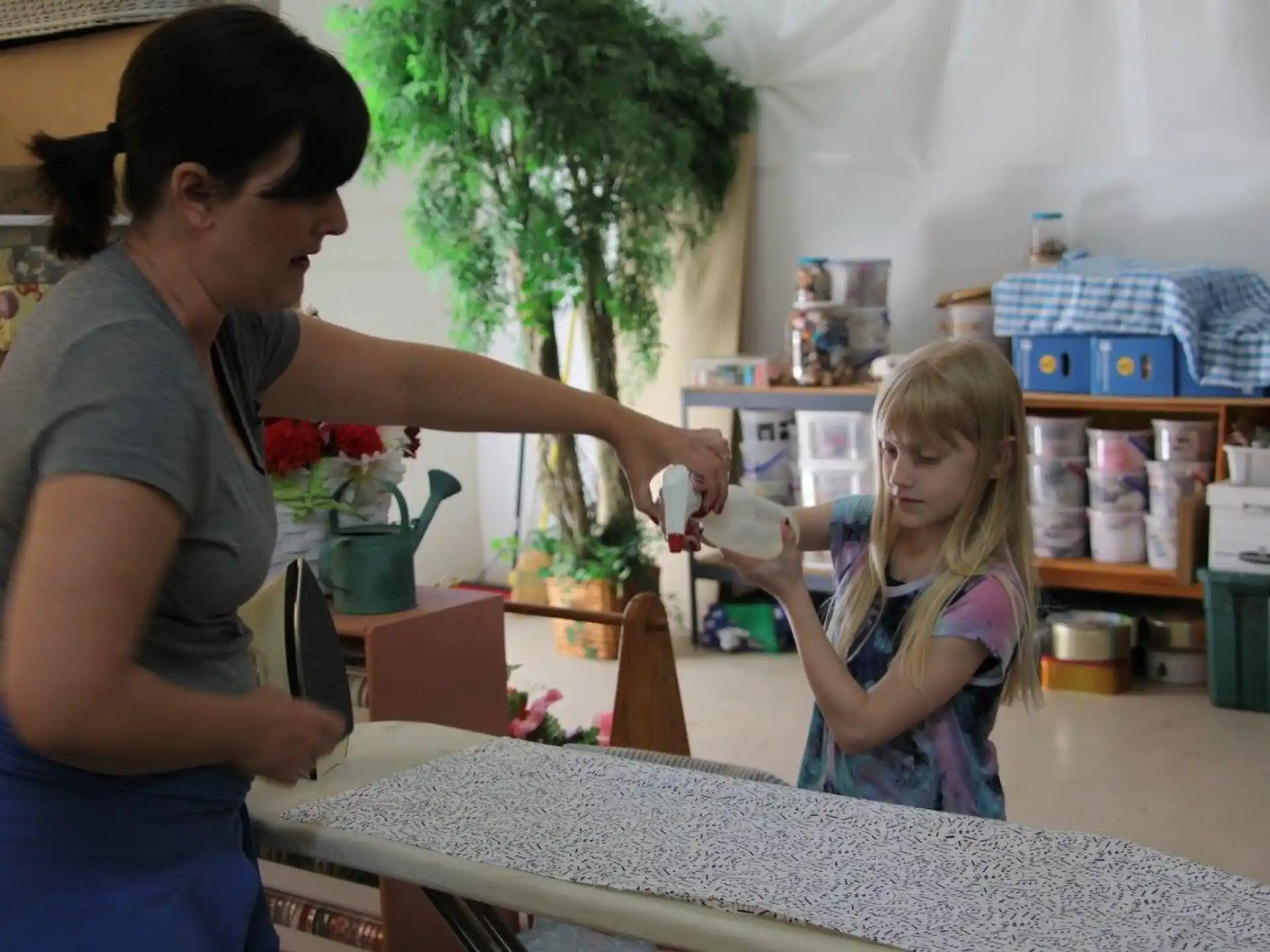 a person and a girl in a room with a table and plants