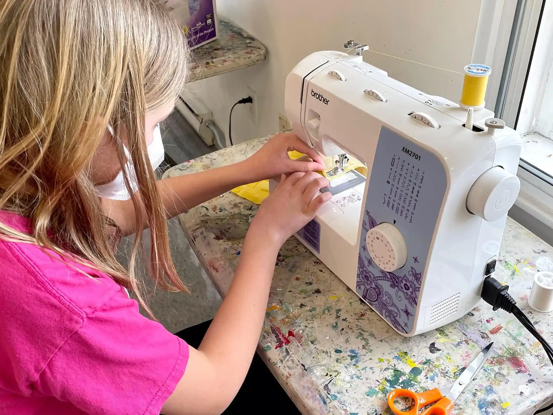 a young girl using a sewing machine