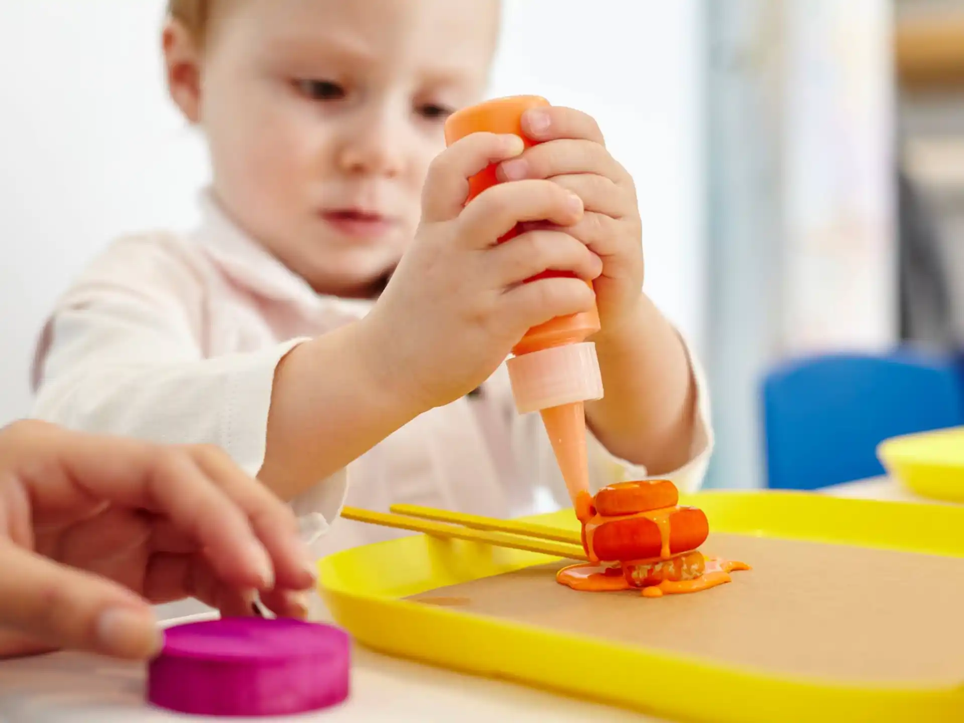 a baby pouring a liquid into a glass