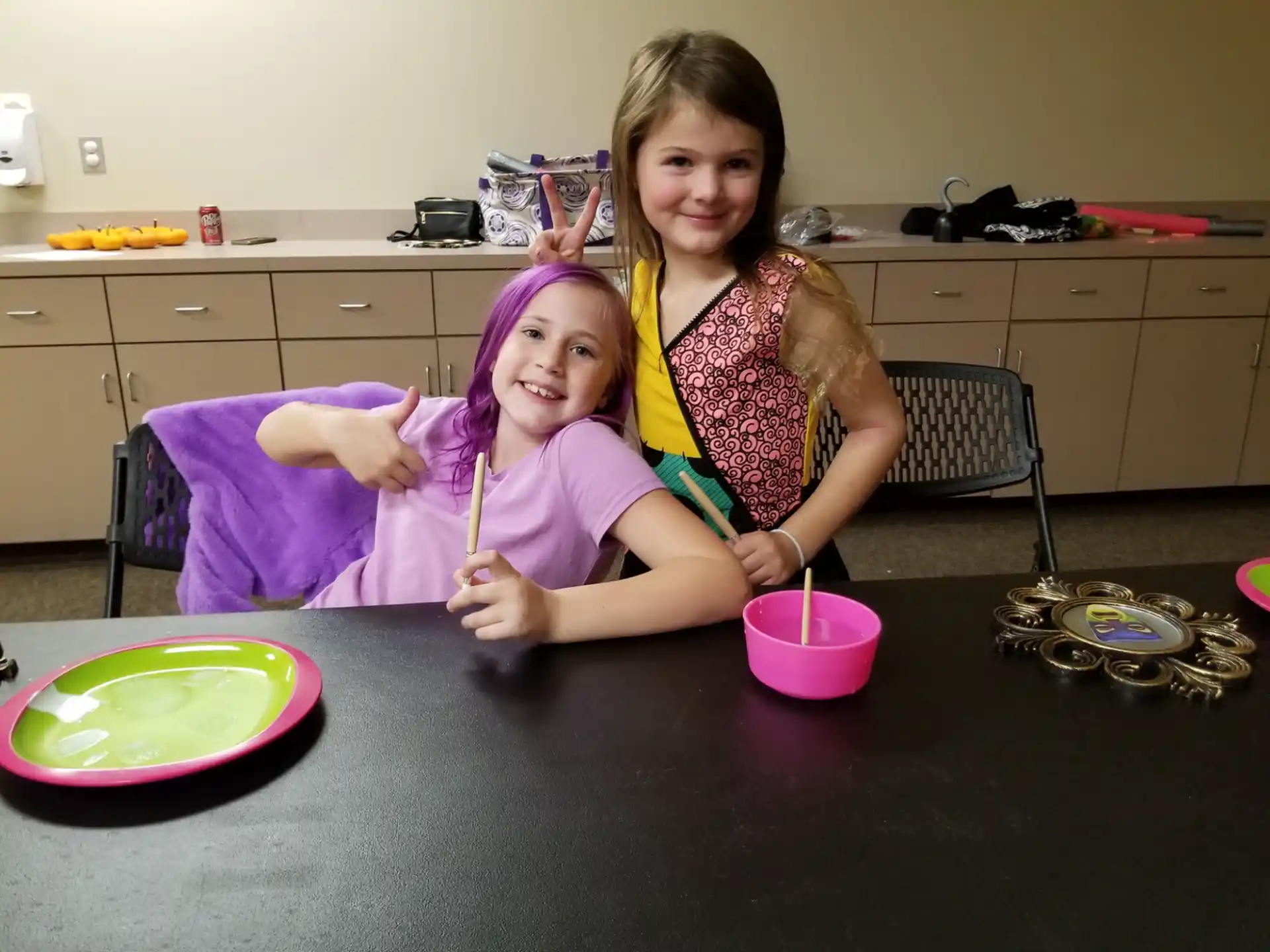 a couple of girls sitting at a table with a plate of food
