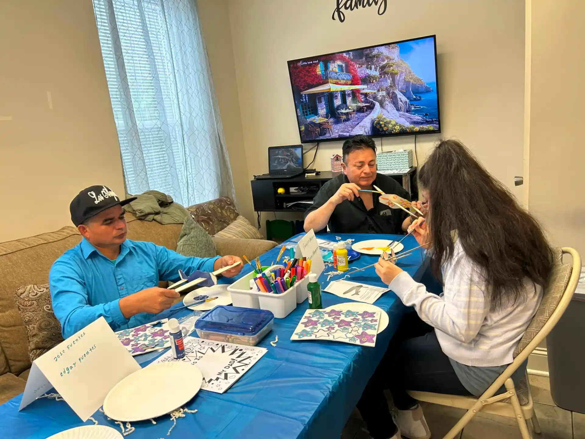 a group of people sitting around a table with a television in the background