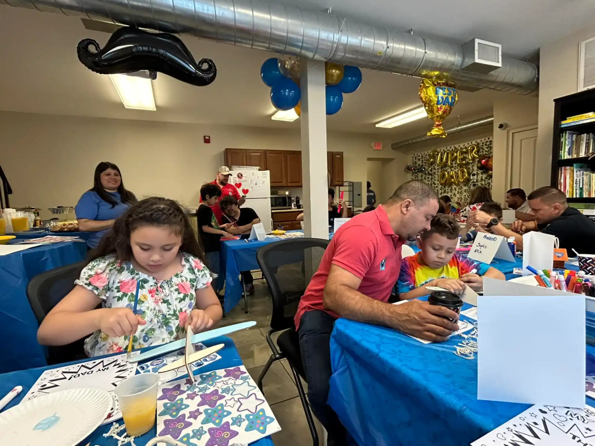 a person and a child sitting at a table with a laptop
