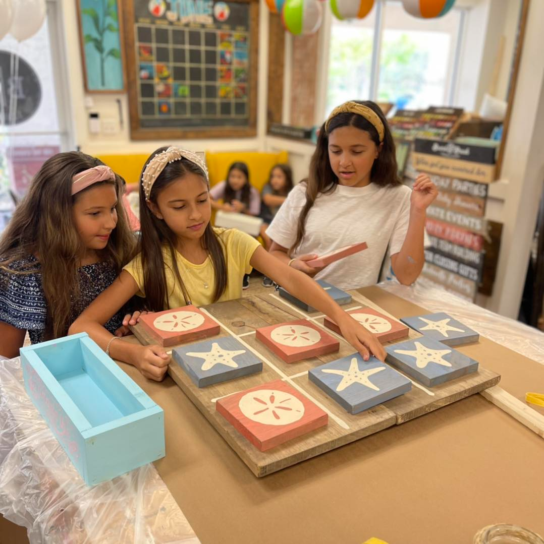 a group of girls sitting at a table with books and a box
