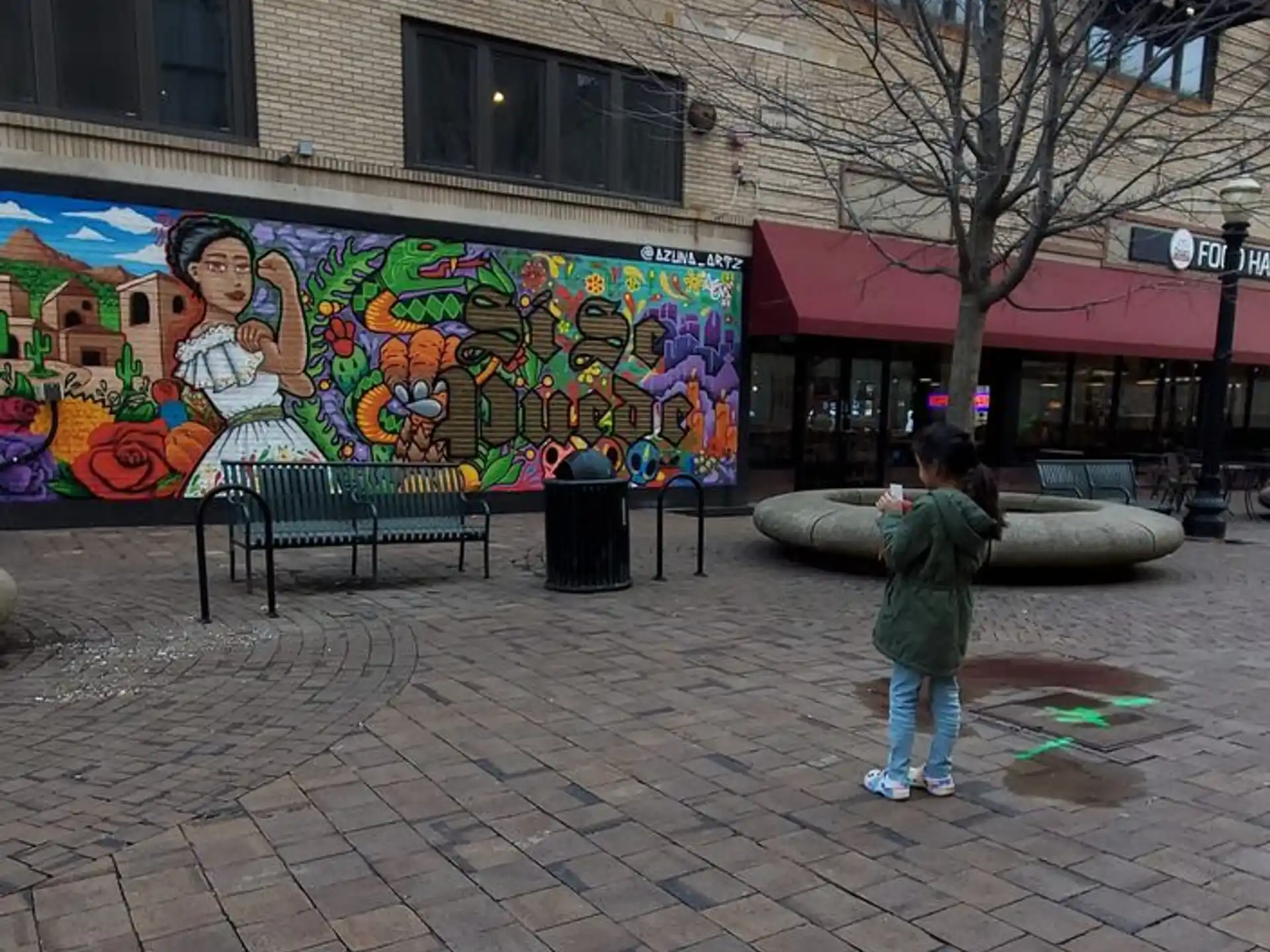 a child standing in front of a mural