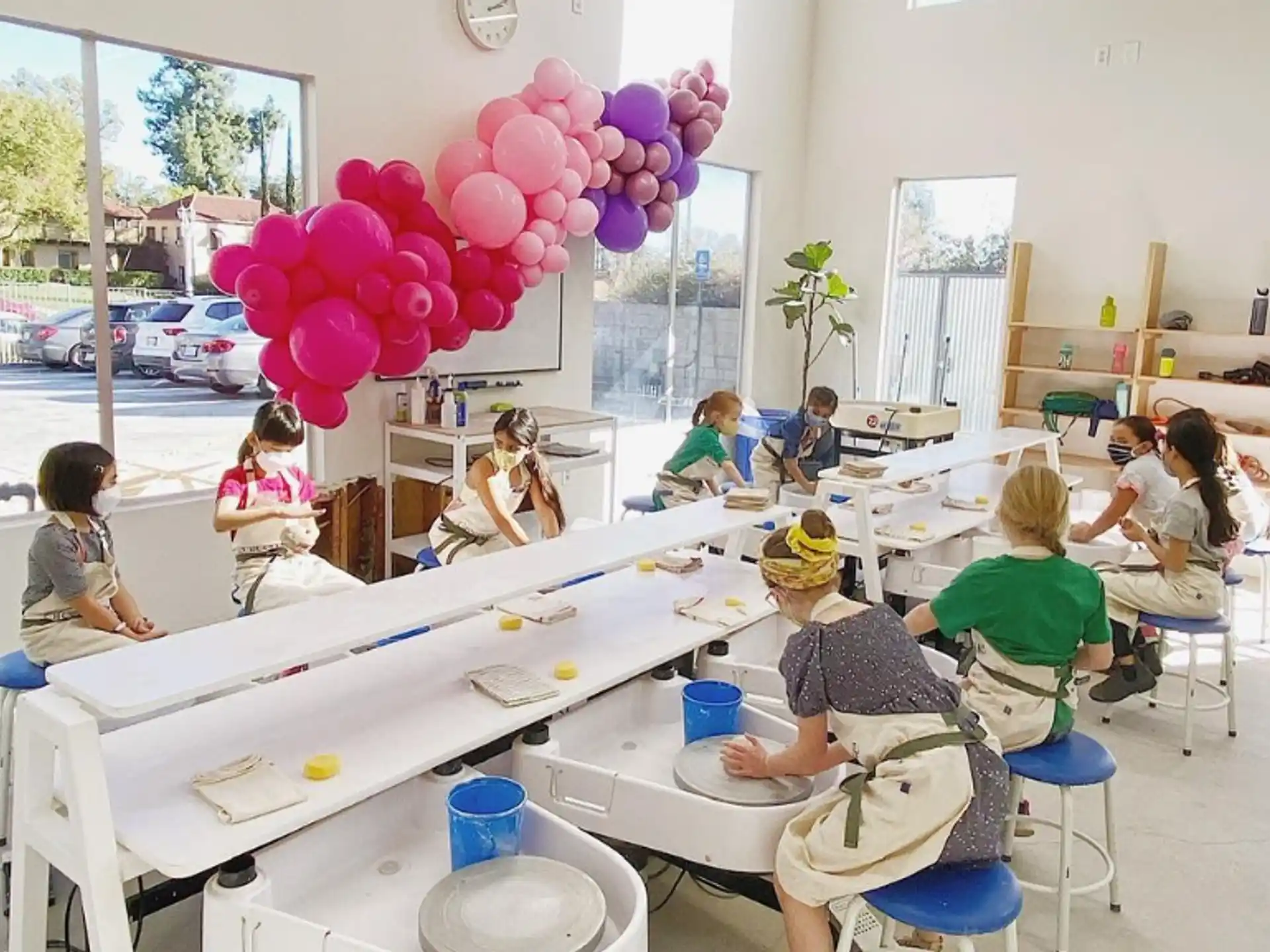 a group of children sitting at a table with balloons