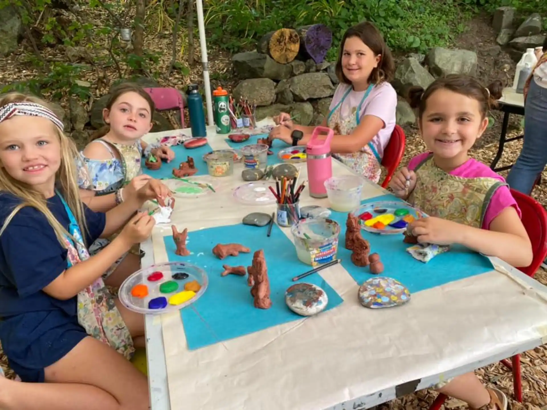 a group of girls sitting at a table with food and drinks