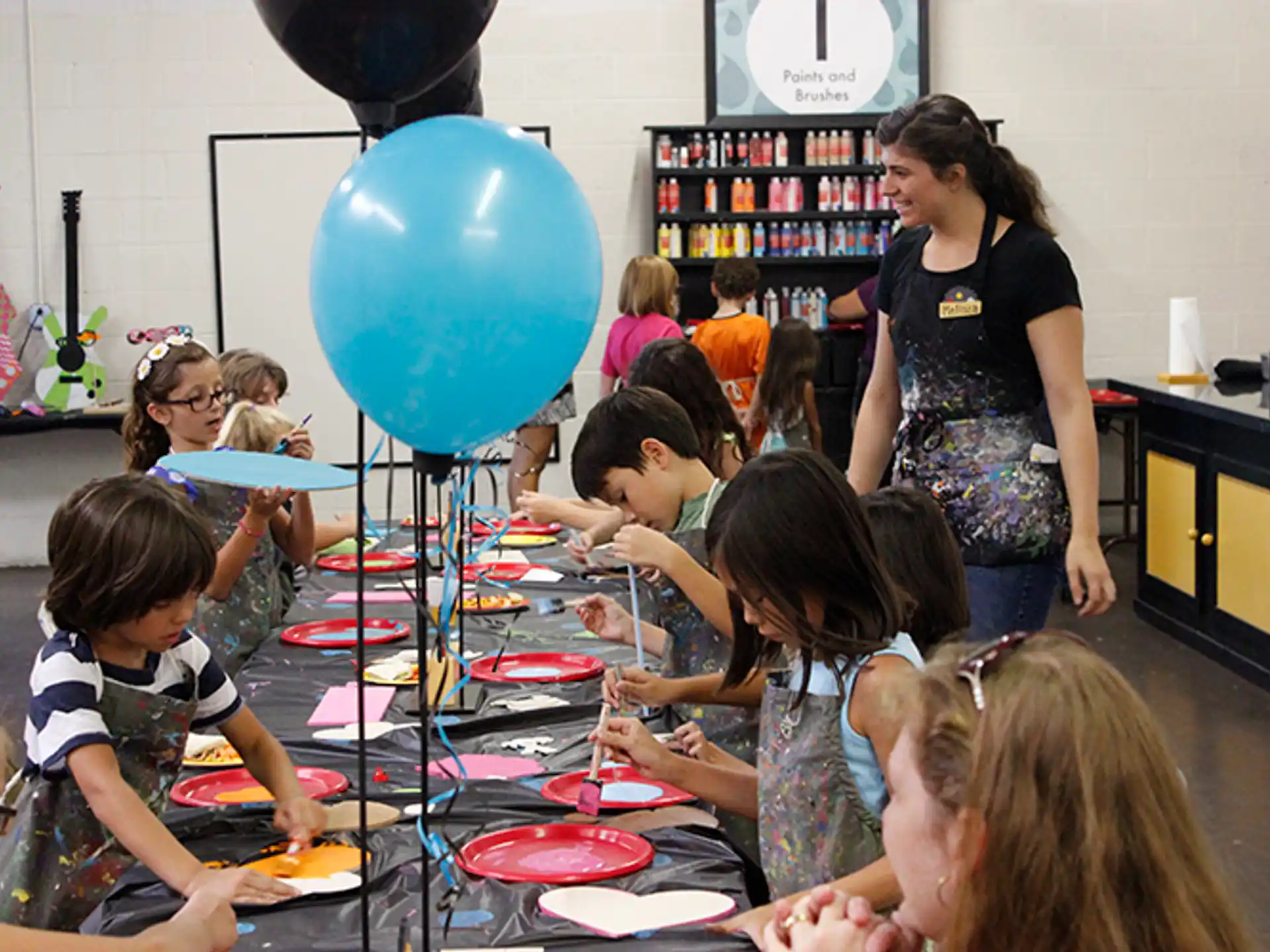 a group of children sitting at a table with a balloon