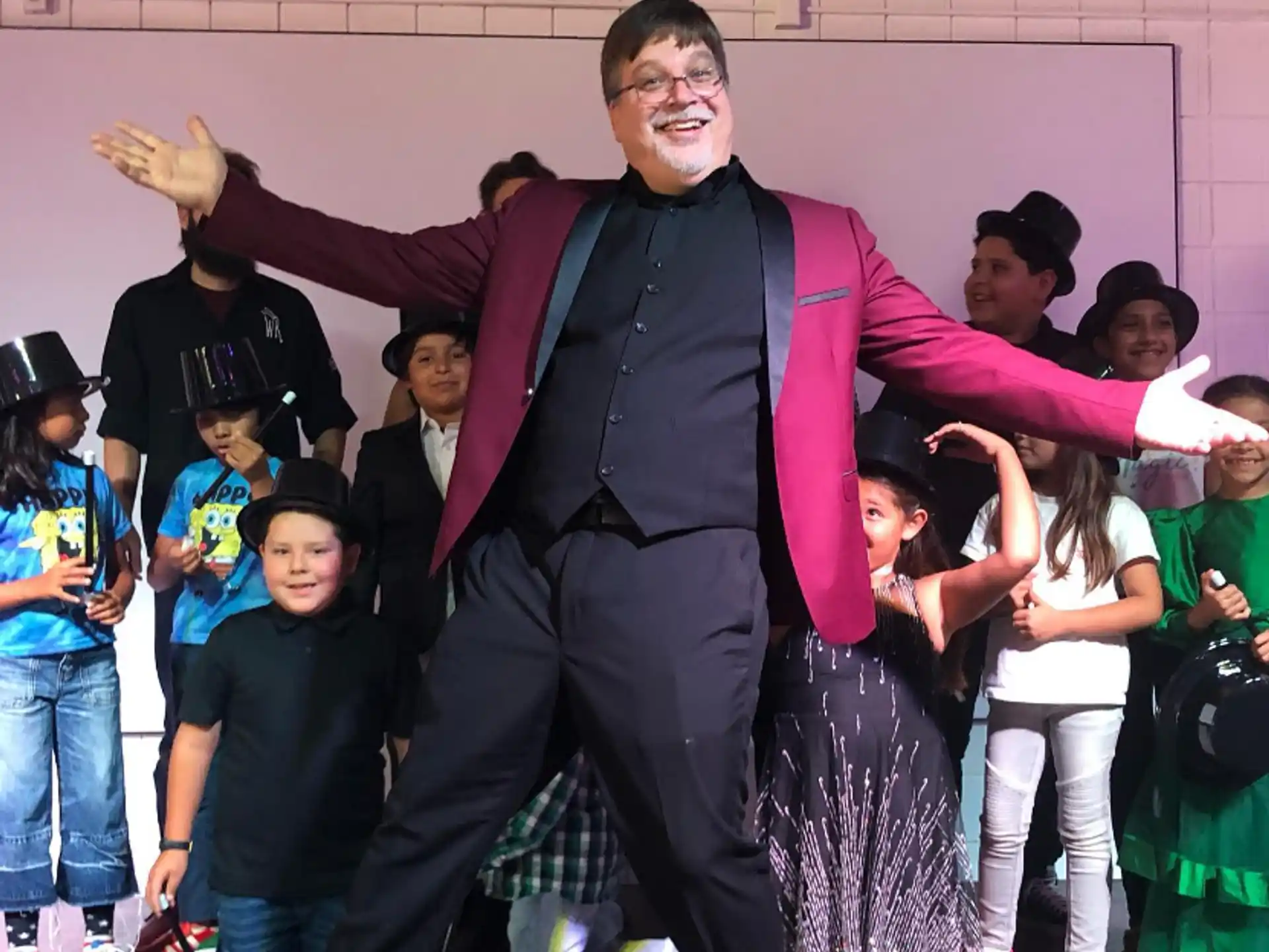a person in a suit with the arms raised in front of a group of people