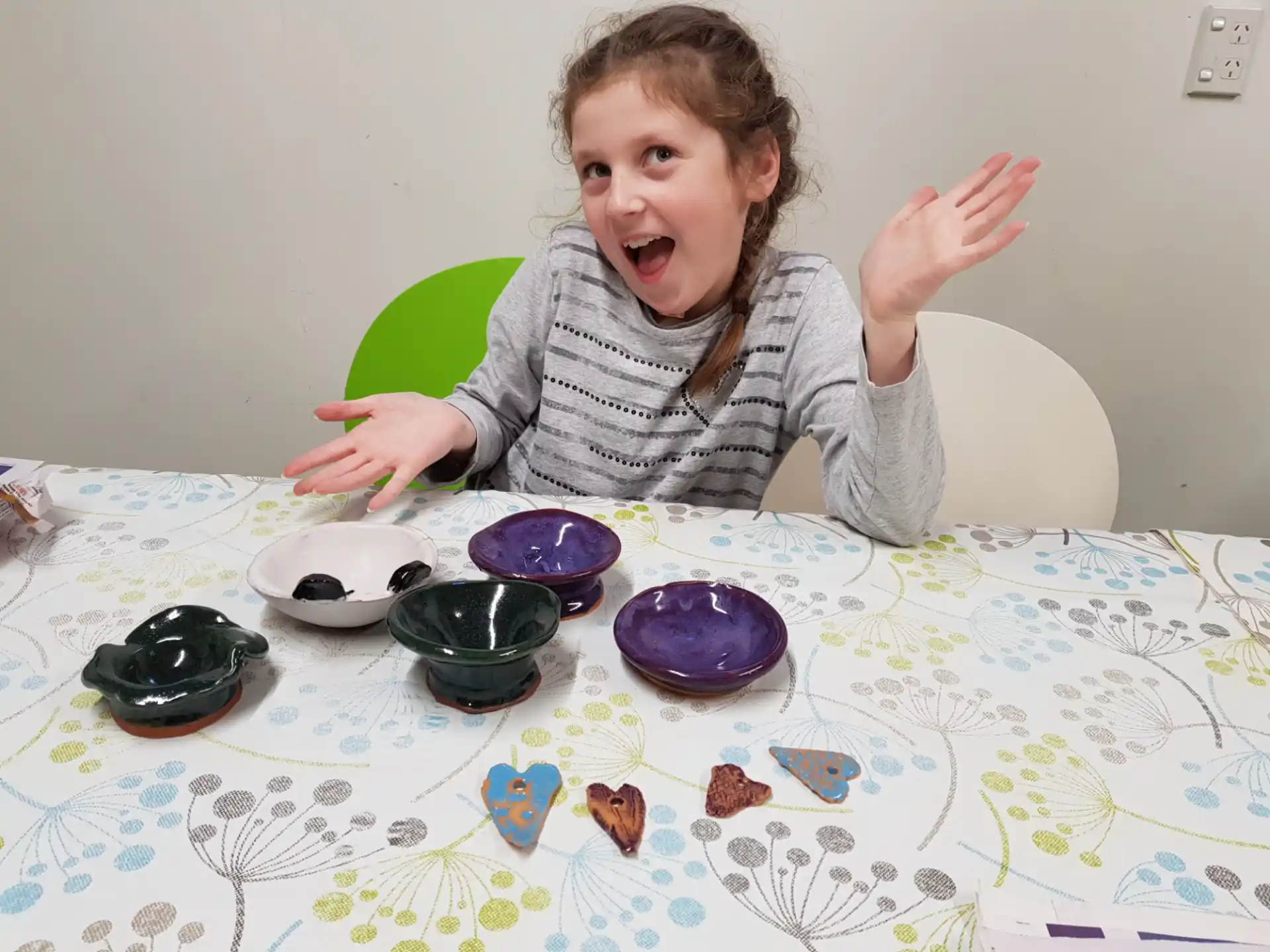 a girl sitting at a table with bowls and a plate of food