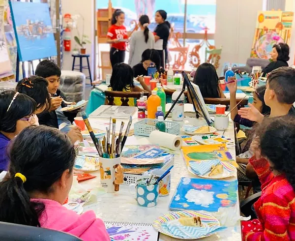 a group of children sitting at a table with art on it