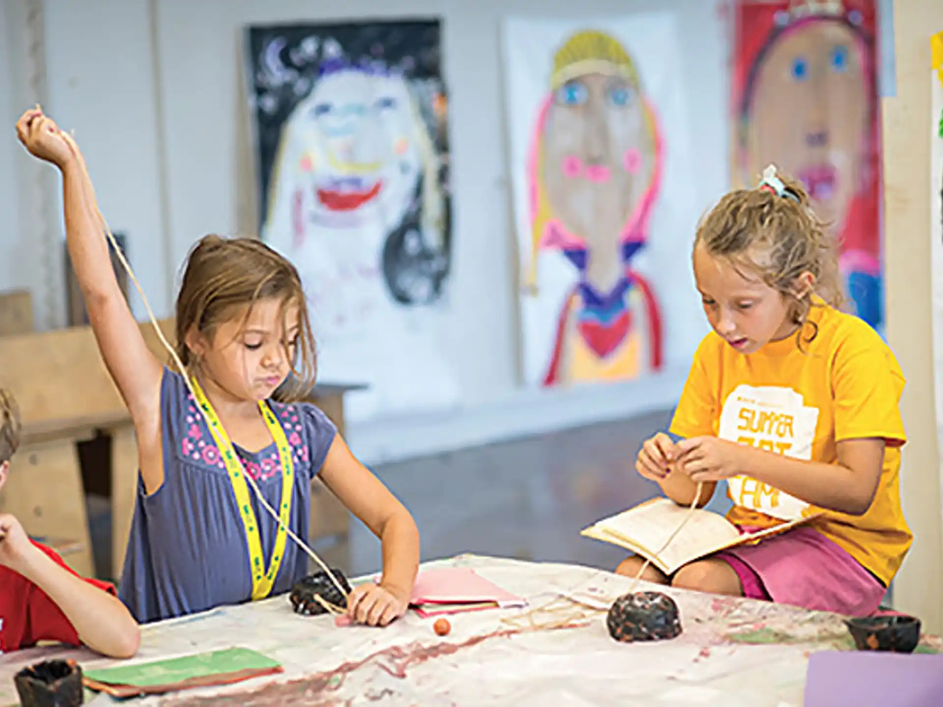 a group of children sitting at a table painting
